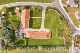Deze karaktervolle fermette in Gistel bevindt zich op een ruim perceel van 5.202 m² en combineert een solide woning met een grote, veelzijdige schuur. Het hoofdhuis werd gebouwd in 2010 en vormt vandaag een uitstekende basis voor wie de eigendom verder naar eigen smaak wil afwerken en moderniseren.<br /><br />Hoewel het interieur op bepaalde vlakken een update kan gebruiken, werd bij de bouw gekozen voor kwalitatieve en duurzame materialen. Zo beschikt de woning onder meer over volle eiken parketvloeren en deuren en een bijzonder stevige constructie. Op het gelijkvloers bevinden zich de inkomhal met gastentoilet, living, eetruimte, veranda, keuken, mudroom/bijkeuken, badkamer en een slaapkamer.<br /><br />De verdieping is momenteel één grote open ruimte en biedt daardoor bijzonder veel potentieel. Met een doordacht ontwerp kunnen hier eenvoudig meerdere bijkomende slaapkamers en één of meerdere badkamers worden gerealiseerd. De oppervlakte laat minstens twee bijkomende slaapkamers toe, maar biedt voldoende ruimte om desgewenst tot vier kamers op deze verdieping te creëren. Hierdoor kan de woning volledig worden afgestemd op de noden van de toekomstige eigenaar.<br /><br />Een bijkomende troef is de grote vrijstaande schuur. Ook deze werd aan de buitenzijde vernieuwd, met onder meer een nieuw dak en vernieuwde muren. De ruimte kan vandaag dienstdoen als ruime garage of opslagplaats, maar biedt eveneens interessant toekomstpotentieel als bureel of praktijkruimte.<br /><br />Buiten sluit een zuidgericht terras aan op de woning, waar dankzij de ligging ook ’s avonds nog van de zon kan worden genoten. Alle aanwezige gebouwen en verhardingen zijn vergund.<br /><br />Een eigendom met een sterke basis, kwalitatieve materialen en vooral veel mogelijkheden voor wie op zoek is naar ruimte en flexibiliteit en de laatste afwerking graag naar eigen hand zet.