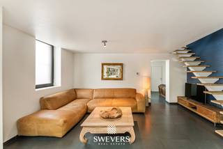 Voor meer info en foto’s, surf naar www.swevers.be – In de Lochtstraat in Bilzen-Hoeselt bevindt zich deze verrassend ruime woning met een warme uitstraling en een praktische indeling. De woning werd oorspronkelijk gebouwd tussen 1900 en 1918 en onderging in 2013 een totaalrenovatie, waardoor karakter en hedendaags comfort hier mooi samenkomen. Met een bewoonbare oppervlakte van 192 m², verdeeld over drie niveaus, biedt deze woning tal van mogelijkheden voor gezinnen, thuiswerkers of wie gewoon graag ruim woont. Op het gelijkvloers geniet u van een gezellige leefruimte van 20 m² en een bijzonder ruime keuken van 44 m² met voldoende plaats voor een grote eettafel. Verder vindt u hier nog een apart bureau, ideaal als thuiswerkplek, hobbyruimte of gelijkvloerse slaapkamer. Vloerverwarming zorgt voor extra dagelijks comfort. De eerste verdieping beschikt over een ruime slaapkamer van 21 m² en een praktische badkamer. Op de tweede verdieping bevinden zich nog twee extra slaapkamers van respectievelijk 19 m² en 17 m², perfect als kinder-, logeer- of hobbykamer. Buiten geniet u van een gezellige tuin met voldoende privacy op een onderhoudsvriendelijk perceel van 2a 53ca. Daarnaast is er een garage aanwezig voor één wagen met extra bergruimte. De ligging vormt een extra troef dankzij de vlotte verbinding naar omliggende gemeenten en de autosnelweg op slechts 5,6 km. Scholen, openbaar vervoer, winkels en ontspanning bevinden zich eveneens vlakbij. Voor meer informatie, bel 012 699 900. Bron bewoonbare oppervlakte: EPC – verslag.