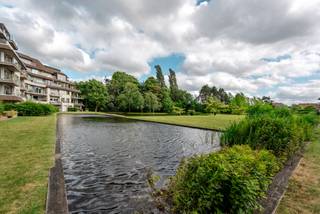 Schitterend gelijkvloers appartement, volledig afgewerkt en nooit bewoond. Hier stapt u binnen in een gloednieuwe, tijdloze leefomgeving van topkwaliteit. Domoticasysteem, op maat gemaakt meubilair en een terras met zicht op de vijver maken dit appartement bijzonder.<br /><br />De inkomhal leidt naar een lichtrijke living met rondom raampartijen, aansluitend op de geïnstalleerde keuken met composiet werkblad en kookeiland. Twee ruime slaapkamers, waarvan één met en-suite badkamer (dubbele wastafel, inloopdouche, apart toilet) en een tweede met eigen wastafel en douche. Een derde kamer is vandaag ingericht als strijkkamer/bureau, maar evengoed bruikbaar als dressing of kinderkamer.<br /><br />Via de living stapt u rechtstreeks het terras op, met zicht op de vijver en het groene domein. Een ondergrondse, afgesloten garagebox met ruimte voor een grote wagen en extra stockage maakt het plaatje compleet. Deze is bij te kopen voor € 40.000<br /><br />Een gloednieuw appartement met deze afwerking en ligging is zeldzaam. Plan snel uw bezoek.<br /><br />Referentie: YP/26069/TK
