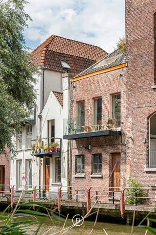 Dit uitzonderlijk gerenoveerd duplex appartement bevindt zich op een unieke historische locatie in het hart van het Patershol. Het appartement combineert hedendaags comfort en hoogwaardige afwerking met een bijzonder woongevoel dankzij het frontale zicht op het water, het terras aan de leefruimte en het ruime dakterras.<br /><br />Gelegen in een kleinschalige residentie met slechts drie entiteiten geniet dit appartement van maximale privacy en het voordeel van geen maandelijkse gemeenschappelijke kosten. De authentieke charme van het Patershol, de gezellige horeca en de nabijheid van het stadscentrum maken dit tot een bijzonder gegeerde locatie.<br /><br />Binnenin staan licht, ruimte en verfijnde afwerking centraal. Grote raampartijen, een patio en een centrale lichtstraat zorgen voor een uitzonderlijk lichtrijk interieur.<br /><br />De inkomhal met ingemaakte kasten en gastentoilet geeft toegang tot de stijlvolle leefruimte met open keuken. De keuken is volledig uitgerust en afgewerkt met een werkblad in kwartsiet natuursteen en hoogwaardige elementen zoals een Quooker kraan. Vanuit de leefruimte geniet u van een prachtig frontaal zicht op het water en heeft u directe toegang tot het terras.<br />Op deze verdieping bevindt zich een slaapkamer met ensuite badkamer, voorzien van een inloopdouche, wastafel en toilet. De badkamer werd afgewerkt met hoogwaardig kraanwerk van Gessi.<br /><br />De architecturale draaitrap leidt naar de bovenverdieping met master bedroom, ingericht met een uitgesproken hotelgevoel. De glazen ensuite badkamer beschikt over een inloopdouche, ligbad en dubbele wastafel. Daarnaast is er een tweede kamer die perfect kan dienen als bureau, kinderkamer of hobbyruimte.<br /><br />De absolute troef van dit appartement is het ruime dakterras met eetruimte en buitenkeuken. Een unieke plek om te genieten van lange zomeravonden, het uitzicht en de charme van historisch Gent.<br /><br />Een uitzonderlijk duplex appartement voor wie op zoek is naar karakter, luxe, privacy en een topligging in het hart van het Patershol.