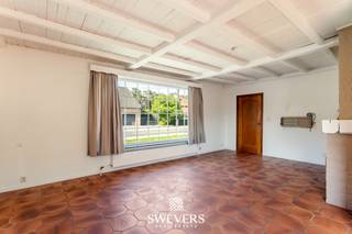 Voor meer info en foto’s, surf naar www.swevers.be – Deze te renoveren bungalow aan Grootveldweg 36 in Koersel biedt een praktische basis voor wie een woning volledig naar eigen smaak wil vernieuwen. De woning werd gebouwd in 1975, beschikt over 121 m² bewoonbare oppervlakte en staat op een perceel van 557 m² met oostelijke oriëntatie. Alles bevindt zich op het gelijkvloers. Via de centrale inkomhal bereik je rechts de leefruimte met keuken, samen circa 44 m². Van hieruit is er toegang tot het overdekte terras achteraan. Links van de hal bevinden zich drie slaapkamers van 8,92 m², 13,28 m² en 8,47 m². Verder zijn er een badkamer, een afzonderlijk toilet en een praktische bergruimte. Naast de woning staat een vrijstaande garage, ideaal voor een wagen, fietsen, gereedschap of tuinmateriaal. Ook de tuin biedt voldoende mogelijkheden om na de renovatie een aangename buitenruimte te creëren. De woning is volledig te renoveren, waardoor je vrij bent om indeling, technieken, materialen en afwerking af te stemmen op je eigen woonwensen. De ligging combineert rustig wonen met bereikbaarheid. Winkels en restaurants bevinden zich op circa 3,5 km, scholen op 3,6 km en het centrum van Beringen op ongeveer 6 km. De snelwegen liggen op circa 6,5 km. Een interessante opportuniteit voor wie op zoek is naar een gelijkvloerse woning met drie slaapkamers en veel renovatiepotentieel. Voor meer informatie, bel 011 255 155. Bron bewoonbare oppervlakte: EPC – verslag.