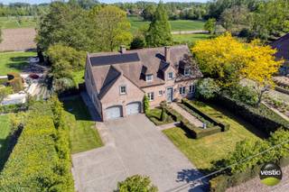 We vinden deze charmante villa met een karaktervolle uitstraling op een ruim perceel van 35a10ca, gelegen aan Russelt 106 in Wellen. De woning bevindt zich langs een vlotte verbindingsweg tussen het centrum van Alken en Wellen, met een snelle aansluiting op de expresweg richting Hasselt en Sint-Truiden. Openbaar vervoer, winkels, scholen en andere voorzieningen liggen in de directe omgeving.<br /><br />De villa werd gebouwd in 2000 met duurzame en kwalitatieve materialen en onderging in 2018 een grondige renovatie. Hierbij werden onder andere een nieuwe keuken en badkamer geplaatst, een bureauruimte op maat ingericht en de tuin volledig opgefrist. Daarnaast werden er twee poorten voorzien langs de servitudeweg en werd het perceel volledig omheind. In 2024 werd de woning verder geoptimaliseerd met de installatie van zonnepanelen (totaal vermogen 8.700 Wp) en een laadpaal.<br /><br />Met een bewoonbare oppervlakte van circa 380 m² en een perceel van 35a10ca staan ruimte, rust en privacy hier centraal. Bovendien beschikt de woning over een energiezuinig EPC-label B met een waarde van 160 kWh/m².<br /><br />Bij het betreden van de woning komt u in een ruime inkomhal met vestiaire en gastentoilet, die toegang biedt tot een stijlvolle bureauruimte op maat. In het interieur werd gekozen voor hoogwaardige en tijdloze materialen zoals massieve eik, travertin (perlato) en natuursteen, wat bijdraagt aan de warme en luxueuze uitstraling van de woning.<br /><br />De lichtrijke leefruimte met zit- en eethoek sluit naadloos aan op de op maat gemaakte keuken. Deze keuken is afgewerkt met een werkblad in Zimbabwe Black natuursteen en uitgerust met kwalitatieve toestellen, waaronder een Falcon inductiefornuis met salamander, hetelucht- en combioven, dampkap Novy, vaatwasser AEG en koelkast AEG.<br /><br />Vanuit zowel de leefruimte als de keuken geniet u van een prachtig zicht op de aangelegde tuin met fruitbomen en achterliggende weilanden. Aansluitend aan de keuken bevinden zich nog een praktische wasplaats met ingebouwde kasten, een aparte douchecel, een koel- en fietsenberging en twee standplaatsen met sectionale poorten, evenals de technische ruimte.<br /><br />Op de eerste verdieping geeft de ruime overloop toegang tot de master bedroom met dressing en een luxueuze badkamer, voorzien van ligbad, een inloopdouche in natuursteen en keramische panelen, dubbele wastafel en toilet. Daarnaast zijn er nog vier ruime slaapkamers en een tweede badkamer met douche, wastafel en apart toilet. Beide badkamers zijn bovendien uitgerust met vloerverwarming.<br /><br />De volledig geïsoleerde zolder, bereikbaar via een luik, biedt extra opslagmogelijkheden.<br /><br />De zuidoost georiënteerde tuin is een absolute troef: met een breedte van ongeveer 40 meter en een volledige omheining geniet u hier van optimale privacy en een open zicht op de achterliggende boomgaard en weilanden. Het (deels overdekte) terras met zonneluifel, de buitenbarbecue, de gezellige zithoek aan de vijver en het tuinhuis maken het geheel compleet.<br /><br />Troeven van de woning:<br />+ Ruim perceel van 35a10ca met een breedte van ca. 40 meter - straatbreedte 30 meter<br />+ Bewoonbare oppervlakte van ca. 380 m² (volgens EPC) - plafondhoogte inkomhal 3,08 m - plafondhoogte living/keuken 2,62 m<br />+ Karaktervolle en tijdloze architectuur<br />+ Luxueuze afwerking met hoogwaardige materialen (massieve eik, travertin, natuursteen)<br />+ Volledig instapklaar dankzij renovatie<br />+ Zeer praktische woonindeling met veel licht<br />+ Energiezuinig (EPC-label B – 160 kWh/m²)<br />+ Zonnepanelen en laadpaal aanwezig<br />+ 5 volwaardige, ruime slaapkamers<br />+ Rustige, groene omgeving met open zicht<br />+ Volledige privacy in de tuin<br /><br />Kortom, deze landelijke villa combineert ruimte, comfort en hoogwaardige afwerking met een uitzonderlijk gevoel van rust en privacy — een ideale thuisbasis voor wie op zoek is naar stijlvol wonen.<br /><br />Wenst u meer informatie of een bezoek ter plaatse? Neem gerust contact op met Stephanie Odeurs via 0474 73 64 84 of via e-mail: stephanie@vestio.com.