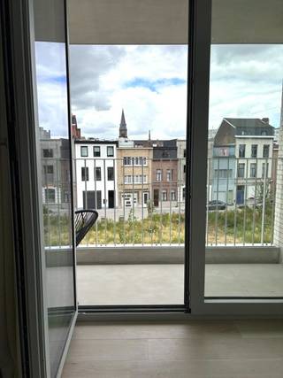 Echte kwaliteit herken je niet aan wat ze laat zien. Maar aan wat ze je laat voelen. De harmonie van een doordachte indeling. De rust van hoogwaardige materialen. Welkom! Het project de Groene Poort is een plek waar je thuiskomt in een rustige, gemeenschappelijke binnentuin, gebruikmaakt van een praktische wasserette en een ruime fietsenberging, terwijl de levendige stad zich letterlijk aan je voordeur afspeelt.<br />Dit instapklare en bijzonder smaakvol gemeubelde appartement is gelegen vlakbij het Lobroekplein, met uitzicht op groen, in de bruisende en volop ontwikkelende Slachthuisbuurt. Een buurt die vandaag al leeft en morgen alleen maar aan waarde wint. Van zodra je binnenkomt, ervaar je de rust van een doordacht interieur. De inkomhal is afgewerkt met een stijlvolle ingemaakte kastenwand die niet alleen elegant oogt, maar ook bijzonder praktisch is. Verder beschikt het appartement over een afzonderlijk gastentoilet, twee volwaardige slaapkamers, een gezellige douchekamer met een modern wastafelmeubel, een praktische berging en een hoogwaardige open Siematic-keuken, volledig uitgerust met kwalitatieve toestellen die aansluit op de leefruimte. De doorlopende keramische parketvloer in combinatie met de aangename vloerverwarming zorgt voor een warme, tijdloze uitstraling in het volledige appartement. Ook buiten krijgt het wonen extra ruimte. Het overdekte terras vormt een natuurlijk verlengstuk van de leefruimte om even ontsnappen aan de dynamiek van de stad… zonder ze ooit echt te verlaten.<br />Ook de ligging is een absolute troef. Op wandelafstand vind je gezellige cafés, restaurants en terrasjes. Een Carrefour Express die zeven dagen op zeven geopend is, een apotheek en tal van andere voorzieningen maken het dagelijkse leven bijzonder comfortabel. Bovendien geniet je van een uitstekende verbinding met het stadscentrum, openbaar vervoer en de belangrijkste invalswegen.<br />Dit appartement is dan ook de perfecte keuze voor wie op zoek is naar een stijlvolle, zorgeloze woonplek waar design, comfort, locatie en levenskwaliteit harmonieus samenkomen.<br />Instapklaar. Volledig gemeubeld. Klaar om jouw volgende hoofdstuk te schrijven. Onmiddellijk beschikbaar - Gem. kosten ca. € 135,-/m incl. provisie voor verwarming - EPB in opmaak