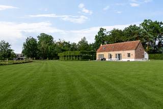 Op een gunstige en vlot bereikbare ligging in Putte bevindt zich deze exclusieve, stijlvol vormgegeven villa, gelegen op een perceel van maar liefst 18.105 m². Een eigendom waar ruimte, licht en verfijning samenkomen in een harmonieus geheel, met alle voorzieningen binnen handbereik.<br /><br />Bij het betreden van het hoofdgebouw wordt u verwelkomd in een lichtrijke inkomhal. De royale leefruimte met grote glaspartijen laat het daglicht rijkelijk binnenstromen en creëert een mooie connectie met de tuin en het omliggende groen. De sfeervolle zithoek met cassette nodigt uit tot ontspannen avonden in alle comfort, aangrenzend de bureauruimte. De leefkeuken beschikt over kwalitatieve toestellen en een hoogwaardige afwerking. Hier is ruim plaats voor een gezellige eethoek met zicht op het terras en de tuin. Aan de keuken grenst een aangename speel- of zithoek. Het gelijkvloers is praktisch ingericht met een ruime, stijlvolle badkamer (uitgerust met een ligbad, inloopdouche en dubbele wastafel), een handige wasplaats/berging met apart toilet en een overdekt terras aan de achterzijde waar u in alle rust kunt genieten.<br />De verdieping biedt via de nachthal toegang tot drie comfortabele slaapkamers en een ruime berging.<br /><br />Aan de achterzijde van het perceel bevindt zich een volwaardig, vrijstaand bijgebouw met aansluitende dubbele carport. Dit bijgebouw is ingericht als een gezellig en compleet appartement, uitgerust met airconditioning, een gezellige woonkamer, eetkamer, kitchenette, een aparte badkamer en een slaapkamer. Ideaal als kangoeroewoning, gastenverblijf, bureau of voor inwonende familie. Ook buiten wordt het unieke karakter van het domein moeiteloos doorgetrokken. De prachtig aangelegde tuin stroomt over in een uitgestrekt perceel met een sprookjesachtige private vijver en een sfeervol bijgebouw aan het water. Een idyllische plek die maximale rust, natuur en privacy uitstraalt.<br /><br />Kortom, een uitzonderlijke en zeldzame opportuniteit voor wie op zoek is naar een karaktervolle, energiezuinige woning met bijgebouw/appartement en een sublieme buitenbeleving in Putte. Contacteer ons voor meer informatie via 0472/22 12 41 of bezoek www.boonstravastgoed.be.<br /><br />Bijzonderheden:<br />- Perceel: 1,8 hectare<br />- Energie: EPC-label B<br />- Troef: Grote private vijver<br />- Parkeren: Carport aanwezig<br />- Bewoonbare oppervlakte: 281 m²<br />- Bijgebouw: Volwaardig appartement<br />- Voorzieningen: Zonnepanelen en airco