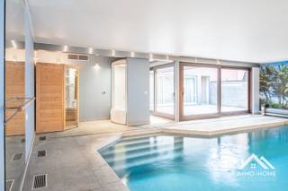 Deze zeer riante woning, 455 m2 bewoonbaar (co-housing?), ontvangt je in een ruime inkomhal (met gastentoilet). Via een wandhoge pivoterende deur kom je zo verder tot in de bijzonder ruime leefruimte met open keuken. Net zoals in de rest van het pand is er voorzien in vloerverwarming- én koeling, waardoor nergens storende elementen aanwezig zijn. In de zithoek is er een grote inbouwhaard aanwezig, en in een hoekje vinden we een mooi verborgen bureel terug. De keuken is voorzien van alle moderne kookcomfort van hoge standaards, en op en aan het dubbele kookeiland is het heerlijk kokerellen voor gasten en familie. Een gekoelde berging maakt hier het plaatje compleet. Op de eerste verdieping is er voorzien in twee heel ruime slaapkamers met een gemeenschappelijk overdekt terras, en met middenin een eerste badkamer met zowel ligbad als inloopdouche (plus een tweede toilet). Op dit niveau vinden we ook een fitness-ruimte terug, met zicht op een eigen overdekt balkon. De bovenste verdieping wordt volledig ingenomen door de master bedroom, met een aanpalende riante badkamer (met een derde toilet) en een grote dressing. Ook hier is er een groot terras aanwezig. De mooiste troef vinden we achteraan het pand : daar is een binnenzwembad voorzien, inclusief sauna en douche. Deze ruimte wordt bereikt via een tussenplaats (ook rechtstreeks bereikbaar vanuit de fitness), waar voorzien is in een bijkeuken en een omkleedruimte (met eigen toilet). In het midden van dit alles ligt een groot buitenterras, waar je geniet van voldoende privacy. Net naast de woning is er parkeerplaats voor meerdere wagens. Inschrijven via mail voor de bezoekdag op donderdag 03/09 naar stefan@immo-home.be.