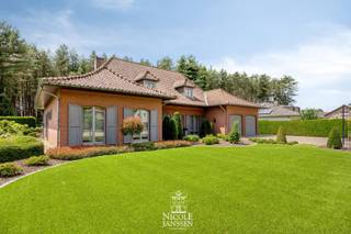 Verscholen in een groene en rustige omgeving bevindt zich deze riante villa. De woning werd degelijk gebouwd en altijd met zorg onderhouden. Doorheen de jaren werd ze smaakvol gerenoveerd met respect voor haar authentieke charme. Het overdekt zwembad, de sauna en het uitgestrekte domein zorgen voor een uitzonderlijke woonbeleving. <br />Een extra troef is dat de woning beschikt over een gunstig EPC-label en een conforme elektrische installatie.<br /><br />=> Ligging<br />De woning is gelegen te midden van de natuur, in een groene en rustige omgeving. Dankzij de vele fiets -en wandelmogelijkheden in de buurt, is dit de ideale locatie voor natuurliefhebbers. Een echte oase van rust, terwijl winkels, scholen en andere voorzieningen vlot bereikbaar blijven. <br /><br />=> Gelijkvloers<br />- Royale inkomhal met keramische tegelvloer en een stijlvolle eiken trap naar de verdieping<br />- Er is ook vestiaireruimte voorzien en een apart gastentoilet met lavabo<br />- Ruime leefruimte met gezellige zithoek voorzien van houthaard en aparte eetplaats<br />- Grote schuiframen zorgen voor een mooie verbinding met de tuin en veel natuurlijk lichtinval<br />- Het behoud van de authentieke elementen zorgt voor een warm en karaktervolle sfeer<br />- Ruime leefkeuken met granieten werkblad, kwalitatieve toestellen en gezellige eetruimtes<br />- Aansluitende berging met inbouwkasten, aansluiting voor wasmachine en droogkast en apart toilet<br />- Praktische bureauruimte aan de voorzijde van de woning<br />- Master bedroom met prachtig zicht op de tuin<br />- Twee bijkomende slaapkamers, ideaal voor wie het comfort van gelijkvloers wonen wenst<br />- Badkamer uitgerust met ligbad, douche en lavabo in een stijlvol badkamermeubel<br /><br />=> Verdieping<br />- Overloop met toegang tot de verschillende kamers<br />- Op deze verdieping bevinden zich nog twee ruime slaapkamers en twee bergzolders<br /><br />=> Kelder<br />- De kelder is toegankelijk via de woning als langs de buitenzijde<br />- Momenteel ingericht met vijf afzonderlijke ruimtes: een grote multifunctionele ruimte, technische ruimte, extra bergruimtes en een ingerichte fitnessruimte <br /><br />=> Tuin<br />- Ruim terras met elektrisch zonneluifel waar je kan genieten van het prachtige uitzicht op de tuin en het omliggende groen<br />- De zuidwestelijk georiënteerde tuin is prachtig aangelegd en volledig omheind voor optimale privacy<br />- Het overdekt zwembad vormt het middelpunt van de tuin<br />- Deze ruimte is tevens voorzien van vloerverwarming<br />- Deze ontspanningsruimte beschikt over een keukenhoek, douche, toilet, kleedkamer en sauna <br />- Charmante pergola met tuinhuis, momenteel ingericht als gezellige lounge- en zithoek om op elk moment van de dag te genieten<br />- Achter de woning bevindt zich meer dan 1,5 hectare bos en weiland, volledig omheind en bereikbaar via een afzonderlijk doorgangsweg aan de achterzijde<br />- Ideaal voor recreatie, dierenliefhebbers of het houden van kleinvee<br />- Dubbele inpandige garage met elektrische kantelpoorten en ingebouwde kastenwand <br /><br />=> Indeling<br />- Gelijkvloers: inkomhal, gastentoilet, woonkamer met eetplaats, keuken, hal, apart toilet, praktische berging/wasplaats, bureelruimte, master bedroom, twee slaapkamers, badkamer<br />- Verdieping: overloop, twee slaapkamers, twee bergzolders<br />- Zolder: nog af te werken naar eigen wens<br />- Kelder: multifunctionele ruimte, technische ruimte, opbergruimtes, ingerichte fitnessruimte