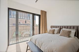 Op de derde verdieping van Waterhuys, binnen de gerenommeerde Kanaalsite van Axel Vervoordt, bevindt zich dit luxueuze appartement van ca. 235 m² met een indrukwekkend terras van ca. 72 m². Architectuur, rust, licht en verfijning komen hier samen in een uitzonderlijke woonomgeving aan het water.<br /><br />Indeling:<br />De royale leefruimte geniet van brede glaspartijen, warme parketvloeren en een directe connectie met het terras. Vanuit de woonkamer en buitenruimte is er zicht op het water.<br /><br />Aansluitend bevindt zich de luxueuze keuken met donker kamerhoog maatwerk, een royaal natuurstenen eiland, geïntegreerde toestellen en subtiele verlichting. Naast de keuken is er een aparte bijkeuken/wasplaats met spoelzone en extra opbergruimte.<br /><br />Het terras vormt een echte verlenging van de leefruimte. Door de royale oppervlakte, houten afwerking en beschutte ligging voelt deze buitenruimte aan als een private loggia, met zicht op het water en de architecturale omgeving van Kanaal.<br /><br />De mastersuite is opgevat als een discrete private wing met ruime slaapkamer, dressing op maat en een serene badkamer met vrijstaand bad, inloopdouche en dubbele wastafel. Daarnaast is er een tweede volwaardige slaapvleugel met slaapkamer, dressing en eigen badkamer, ideaal als gastenverblijf of suite voor een inwonend kind.<br /><br />Bijzonderheden:<br />- Zicht op het water vanuit leefruimte en terras<br />- Luxueuze keuken met natuurstenen eiland<br />- Aparte bijkeuken/wasplaats<br />- Mastersuite met dressing en badkamer<br />- 2e slaapkamer met dressing en eigen badkamer<br />- 3 garageplaatsen verplicht bij aan te kopen aan € 25.000 per plaats
