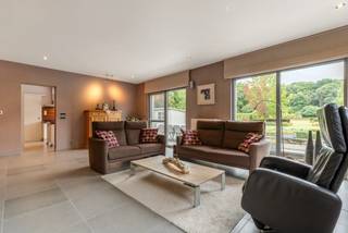 Moderne, vrijstaande woning op perceel van ca. 2.072 m² dicht bij het centrum van Tessenderlo, nabij supermarkt, winkels, openbaar vervoer,.. De woning is tegelijkertijd ook erg rustig gelegen, met natuurgebied aansluitend achteraan het perceel. De woning werd gebouwd in 2005. Ze omvat mooie open leefruimten, 6 slaapkamers, 2 badkamers, een bureauruimte, multifunctionele zolder, een dubbele inpandige garage en een groene tuin rondom.<br /><br />Gelijkvloers:<br />U betreedt de woning via de lichtrijke inkomhal met gastentoilet. De hal geeft toegang tot de zeer ruime en lichte woonruimte. Deze omvat een eethoek, zithoek en bureauruimte met hoog plafond dat ruimtelijk effect creëert. De bureauruimte zit verweven in de leefruimtes, afgescheiden door een muurtje. De bureau is vindingrijk verborgen in de inbouwkast. De keuken bevindt zich links langs de woonruimte en is voorzien van alle hedendaags comfort en gaskookplaat. Via de grote schuiframen in woonkamer en keuken kan u het zuid gerichte terras betreden. Na de keuken volgt de wasplaats met berging en inpandige garage met voldoende ruime voor 2 wagens. Vanuit de garage is er toegang tot de kelder. Gelijkvloers is er vervolgens ook een badkamer met douche en wastafel. <br /><br />Verdieping:<br />De trap biedt vanuit de inkomhal toegang tot de bovenverdieping. Hier treft u 4 ruime slaapkamers. Een badkamer voorzien van inloopdouche en dubbele lavabo. Verder nog een apart toilet op de nachthal. De zolder is te bereiken via een vaste trap. Deze ruimte kan multifunctioneel ingezet worden o.a. extra slaapkamer, bureau, speelruimte, hobbykamer… <br /><br />Tuin:<br />De tuin op het zuiden is volledig ingesloten en biedt privacy. Tuinberging en tuinhuis aanwezig. Op het zonneterras met vijver aan de woonruimte/keuken is het zalig genieten tijdens de tussenseizoenen en de zomer. De tuin is prachtig aangelegd, voorzien van verschillende perkjes. Het perceel sluit aan op achterliggend natuurgebied. <br /><br />Bijzonderheden:<br />- Rustige natuurligging nabij het centrum<br />- Rolluiken<br />- 24 zonnepanelen met certificaten <br />- Regenwaterput, aangesloten op toiletten, wasmachine en buitenkraantjes <br />- Ruime kelder<br />- Zuid georiënteerd <br />- Grote zolderruimte met vaste trap