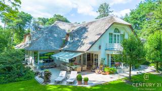 <p><strong>Karaktervol landhuis met prachtig aangelegde tuin, bijgebouw en extra naastliggend bouwperceel van ca 2077m² met verweven tuin optioneel bij aan te kopen – uniek woonaanbod op toplocatie</strong></p>
<p>In een residentiële en rustige omgeving wacht dit uitzonderlijk goed onderhouden landhuis op haar nieuwe bewoners. Gelegen op een royaal dubbel perceel met een schitterend aangelegde en volgroeide tuin, biedt deze eigendom een unieke combinatie van charme, ruimte en veelzijdigheid.<br /><strong>Bovendien geniet u van een uitstekende bereikbaarheid: op slechts 25 minuten rijden van zowel Eindhoven (NL) als Antwerpen (BE)</strong> – een ideale ligging voor wie centraal, maar toch in alle rust wil wonen.</p>
<p>Via de ruime inkomhal met gastentoilet en aparte bureauruimte betreedt u de sfeervolle leefruimte. De gezellige open haard, de brede raampartijen en de naadloze overgang naar de eetkamer zorgen voor een warme, huiselijke sfeer met overal zicht op de prachtige tuin. De volledig uitgeruste keuken is aangenaam ruim en beschikt over een aansluitende berging.</p>
<p>Op de eerste verdieping bevinden zich vier volwaardige slaapkamers en drie badkamers. De masterbedroom beschikt over een eigen inloopdressing, een royale badkamer én een privé-sauna – een ware wellnessbeleving aan huis.</p>
<p>Een bijzonder pluspunt is het multifunctionele bijgebouw, dat bestaat uit een ruime garage met drie poorten en meer dan voldoende opbergruimte. De bovenverdieping van dit gebouw is ingericht als hobbyruimte met een gezellige bar, douche en apart toilet – ideaal als gastenverblijf, atelier, of als zelfstandige ruimte voor inwonende tieners of hulp. Deze verdieping is bereikbaar via een aparte buitentrap.</p>
<p>De tuin is werkelijk een parel: aangelegd als een rustgevend park met vijvers, wandelpaadjes en idyllische zithoekjes vormt het geheel een oase van groen en stilte. Dit extra perceel biedt tevens potentieel voor wie toekomstgericht denkt aan bouwen of uitbreiden. Voor meer informatie over de villa met inbegrip van het optionele perceel verwijzen we u door naar onze eigen website.</p>
<p><strong>Kortom: een unieke kans voor wie op zoek is naar een karaktervol landhuis met veel ruimte, privacy, uitstekende bereikbaarheid en een uitzonderlijk mooie buitenomgeving.</strong></p>