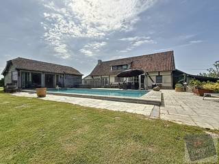 Ontdek deze uitzonderlijke woning, genesteld in het groen aan de Slaapstraat 29 in Alken, op een volledig privatief perceel van maar liefst 11.974 m². Hier ervaart u ultieme rust, absolute privacy en royale leefruimte – een permanente vakantiesfeer in uw eigen huis. Met een bewoonbare oppervlakte van 297 m² (volgens EPC) biedt deze villa een perfecte mix van elegantie, comfort en functionaliteit.<br /><br />De woning verwelkomt u met een ruime inkomhal en een aparte bureauruimte, gevolgd door een gastentoilet, een lichte eetkamer en een gezellige leefruimte met doorkijkhaard. De volledig uitgeruste keuken grenst aan een lichtrijke veranda, ideaal om het hele jaar door te genieten van het uitzicht op de groene tuin. Op het gelijkvloers bevinden zich daarnaast twee slaapkamers met directe toegang tot het terras, een garage met zolderberging en een praktische wasruimte met uitgang naar de tuin.<br /><br />Het buitenleven wordt hier naar een hoger niveau getild: het royale terras met een ingebouwd zwembad en een stijlvol poolhouse met bar vormt het absolute pronkstuk van de woning – perfect voor zomerse ontspanning en sfeervolle avonden met vrienden en familie.<br /><br />Op de verdieping zorgen een open vide, een luxueuze badkamer met ligbad en douche, en een extra slaapkamer met airco voor comfort en privacy. Dankzij zonnepanelen en een warmtepomp combineert deze woning haar authentieke charme met moderne, energiezuinige technologie. Het EPC bedraagt 322 kWh/m² jaar (label D).<br /><br />Een unieke kans voor wie verlangt naar ruimte, natuur en serene rust op een toplocatie in Alken.<br /><br />🔑 Laat u betoveren – contacteer ons vandaag nog voor een exclusief bezoek.