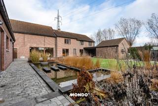 Bent u op zoek naar een zeldzame combinatie van absolute privacy, landelijke grandeur en een toplocatie op een boogscheut van Brussel? Dit indrukwekkende domein op de grens van Wemmel en Relegem biedt een levensstijl die weinigen gegeven is. Terwijl u geniet van het panoramische groen, bevindt u zich op slechts enkele minuten van de belangrijkste verbindingsas (Ring/A12/E40) van het land.<br /><br />Ruimte is de nieuwe luxe. 1,56 ha in de rand is nu al schaars; straks onvindbaar. Een waardestijging hier geen vraag, maar een zekerheid.<br />De omgeving ondergaat momenteel een metamorfose: de afbraak van de hoogspanningslijnen door Elia is gestart, wat de esthetische en commerciële waarde van dit vastgoed onmiddellijk naar een hoger niveau tilt. Een buitenkans voor wie strategisch kijkt.<br /><br />De zuidgerichte woning in charmante hoevestijl (gerenoveerd in 2000) is ontworpen voor ruimte en licht:<br />Riante woning: 4 tot 6 slaapkamers, ideaal voor grote gezinnen of een kangoeroewoning.<br /> Een vrijstaand zwembadgebouw van 150 m² met binnenzwembad en jacuzzi.<br /><br />Een groot werkatelier, wijnkelder met buitenkeuken en een ruime garage. Perfect voor een vrij beroep, een luxueuze B&amp;B of een creatieve studio.<br /><br />Met ruim 1,5 hectare aan eigen grond is dit een paradijs voor dierenliefhebbers. Omliggende weilanden kunnen desgewenst extra worden aangekocht.<br /><br />Moderne stallen (2007), een gedraineerde piste/paddock en uitgestrekte weilanden met een aparte toegang.<br /><br />De ligging in de regio Wemmel/Relegem is uniek. U combineert de prestigieuze uitstraling van de Rand met een ongeziene bereikbaarheid. Dit is geen huis, dit is een bestemming.<br /><br />Ontdek de mogelijkheden van dit unieke domein tijdens een privérondleiding. Ontdek de woning nu alvast virtueel https://my.matterport.com/show/?m=zswZqoTwjPB<br />Contact: Tim 📞 0483 60 60 60<br />✉️ Tim@mondovastgoed.be<br /><br />Mondo Vastgoed – Makelaars, maar anders!