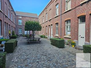 Deze charmante, gerenoveerde beluikwoning in de Bandelierstraat combineert karaktervol wonen met een centrale ligging in Gent. De woning maakt deel uit van een gezellig woonerf met 18 gelijkaardige woningen, gegroepeerd rond een gemeenschappelijke binnenplaats.<br /><br />Net die binnenplaats geeft het geheel zijn bijzondere sfeer: rustig en gezellig, met een fijn buurtgevoel waar bewoners elkaar nog kennen.<br /><br />De woning is instapklaar en praktisch ingedeeld over drie niveaus.<br /><br />Op het gelijkvloers bevinden zich de leefruimte, de ingerichte keuken en de badkamer met douche en toilet. De eerste verdieping biedt plaats aan een ruime slaapkamer, terwijl zich op de tweede verdieping een tweede slaapkamer bevindt.<br /><br />Daarnaast kunnen bewoners gebruikmaken van een gemeenschappelijke, afgesloten fietsenberging.<br /><br />De ligging nabij Gent-Dampoort en Dok Noord zorgt voor een vlotte bereikbaarheid, met het centrum van Gent, winkels, horeca en openbaar vervoer binnen handbereik.<br /><br />Indeling:<br />Gelijkvloers: leefruimte, ingerichte keuken en badkamer met douche en toilet<br />Eerste verdieping: slaapkamer 1<br />Tweede verdieping: slaapkamer 2<br />Gemeenschappelijke afgesloten fietsenberging<br /><br />Praktisch:<br />Beschikbaar vanaf 1 oktober<br />Huurprijs: € 925/maand<br />Provisie: € 50/maand<br />EPC: 252 kWh/m²<br /><br />Zin in een bezoekje?<br />Aarzel dan niet ons te contacteren!