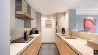 Op de Koningslaan bevindt zich dit verzorgd en lichtrijk appartement met drie slaapkamers en een westgericht terras. Danzij de brede raampartijen (6,4 m gevelbreedte) en de zonnige gevel geniet de leefruimte de hele namiddag van een mooie lichtinval. <br />De woonkamer is voorzien van vier elektrische stores met afstandsbediening, en het volledige appartement kreeg in 2024 een nieuwe LED-verlichting met talrijke dimmers voor een warme, regelbare sfeer. De open keuken met keukeneiland sluit harmonieus aan bij de eet- en zithoek.<br />Achteraan bevinden zich twee ruime slaapkamers, elk met hun eigen ensuite badkamer. De hoofdbadkamer is uitgerust met een jacuzzi voor extra comfort. De derde slaapkamer biedt plaats voor een stapelbed en een uitklapbaar bureau.<br />Daarnaast is er een aparte wasplaats met een nieuwe condensatieketel op gas (vervangen in 2022). <br />Extra troeven zijn de ingemaakte kasten, nette afwerking en het ruime westgerichte terras.