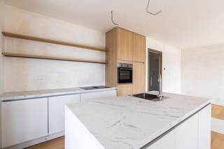 <p><strong>Residentie Tamboer – uw eigen ritme, midden in Turnhout</strong><br />De dag begint met licht dat langs twee kanten de leefruimte binnenvalt. U drinkt koffie met zicht op de stad, wandelt later naar de Grote Markt en komt ’s avonds thuis op een terras waar de laatste zon nog blijft hangen. Dat is het leven in dit penthouse van Residentie Tamboer: de stad dichtbij, met thuis alle ruimte om tot rust te komen.</p>
<p>De residentie dankt haar naam aan de tamboer, de trommelaar die het ritme aangeeft en de stoet voorgaat. Ook hier draait alles om ritme: de levendigheid van Turnhout wanneer u die opzoekt, en de rust van uw eigen plek wanneer u thuiskomt. Net binnen de ring woont u bij water, groen en wandelpaden, met de Grote Markt en het Stadspark op wandelafstand.</p>
<p><strong>Een terras dat mee leeft met uw dag</strong><br />Dit appartement biedt 114 m² bewoonbare oppervlakte en maar liefst 61 m² aan zuid en west georiënteerde terrassen. Het terras loopt rond het appartement en biedt plaats aan meerdere zithoeken: een tafel om buiten te eten, een plek om te lezen, of allebei. Dankzij de zuid en westelijke oriëntatie geniet u van de zon op elk moment van de dag. Tegelijkertijd biedt het overdekt terras schaduw wanneer u daar behoefte aan heeft.</p>
<p>Binnen vormen de zithoek, eetruimte en stijlvolle keuken één open leefruimte. In de leefruimte is er een aangename bureauhoek. Grote ramen brengen aan twee zijden daglicht binnen en verbinden het interieur met het terras. De lichte eiken parketvloer geeft de leefruimtes een warme, tijdloze uitstraling.</p>
<p>Ook de drie slaapkamers hebben toegang tot de terrassen. De hoofdslaapkamer beschikt over een eigen badkamer. Voor de twee andere kamers is er een aparte douchekamer. Richt ze in als slaapkamers, bureau, dressing of hobbyruimte: de indeling geeft u de vrijheid om het appartement aan uw leven aan te passen.</p>
<p><strong>Groot in mogelijkheden, aangenaam in schaal<br /></strong>Residentie Tamboer combineert eigentijdse architectuur met warme materialen en groene gevels. De residentie is opgedeeld in compartimenten met elk een eigen trap en lift. Zo maakt u deel uit van een groter woonproject, terwijl u de gemeenschappelijke delen met slechts een beperkt aantal andere appartementen deelt.</p>
<p>Op het gelijkvloers is een ruime fietsenstalling voorzien. Uw wagen parkeert u in de afgesloten parkeerkelder.</p>
<p>De vraagprijs van dit appartement bedraagt € 409.400 exclusief kosten. Parkeerplaatsen zijn verkrijgbaar vanaf € 20.900 en bergingen vanaf € 4.500. Inclusief btw, registratierechten, notariskosten, één parkeerplaats en één berging bedraagt de totale aankoopprijs circa € 528.000.</p>
<p>Achter Residentie Tamboer staat DC Belgium, een ervaren Belgische projectontwikkelaar met aandacht voor woonkwaliteit en groen. Van uw eerste kennismaking tot de afwerking van uw appartement wordt u persoonlijk begeleid.</p>