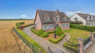 Gelegen op een uitzonderlijke locatie waar rust en open vergezichten samenkomen, onderscheidt deze standingvolle villa zich als een zeldzame opportuniteit voor wie op zoek is naar een verfijnde levensstijl met ruimte, comfort en ontwikkelingspotentieel. Bij binnenkomst wordt u verwelkomd in een elegante inkomhal die leidt naar ruime leefruimtes badend in natuurlijk licht. De royale leefruimte, met brede openingen naar zowel de voor- als achtertuin, creëert een warme en lichtrijke sfeer. Deze sluit naadloos aan op een grote, zorgvuldig ingerichte keuken, aangevuld met een praktische bijkeuken, waarin esthetiek en functionaliteit perfect samenkomen. Op het gelijkvloers bevindt zich bovendien een volwaardige slaapkamer, ideaal voor dagelijks gebruik of het ontvangen van gasten. Op de verdieping beschikt de nachtruimte over drie comfortabele slaapkamers en een ruime badkamer uitgerust met een douche, een ligbad en dubbele wastafels. De ruime overloop biedt tal van inrichtingsmogelijkheden, zoals een stijlvolle bureau of een multifunctionele ruimte. De zolderverdieping, volledig ingericht in 2026, opent nieuwe perspectieven met twee extra kamers en een tussenruimte, die volledige vrijheid bieden voor het creëren van privé-suites, werkruimtes of andere indelingen naar wens.<br /><br />Buiten komt de villa volledig tot haar recht. Een groot zuidwestgericht terras nodigt uit tot ontspanning en biedt een prachtig uitzicht over de omliggende velden, met een uniek panorama dat met de seizoenen mee evolueert. Een volledig uitgeruste barbecuezone maakt dit gezellige geheel compleet, ideaal voor aangename momenten met familie en vrienden. Een deel van het terrein werd doordacht afgescheiden om ruimte te creëren voor dieren, een moestuin of andere projecten naar wens, en biedt zo extra ontwikkelingsmogelijkheden. De volledig onderkelderde woning verhoogt de aantrekkingskracht verder met een ruime garage, veel bergruimte, een praktische wasruimte en een zeer grote polyvalente ruimte die kan worden ingericht als speelkamer, hobbyruimte of atelier, met de mogelijkheid tot het voorzien van een extra badkamer en minibar. Daarnaast is er ook een fitnessruimte met douche aanwezig voor optimaal wooncomfort. De villa is uitgerust met PVC-ramen met dubbele beglazing en beschikt over een modern verwarmingssysteem met een condenserende gaswandketel, wat garant staat voor energie-efficiëntie en dagelijks comfort. Gebouwd in 1979 en zorgvuldig gerenoveerd in 1998 en 2024, werd deze eigendom steeds perfect onderhouden. Het is meer dan een woning; het is een echte levensstijl, waarbij elk detail werd doordacht om een uitzonderlijke woonomgeving te bieden. Bent u op zoek naar een ruime woning, ideaal gelegen en met tal van mogelijkheden? Dan kan deze villa wel eens uw toekomstige thuis worden.<br />