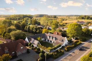 <div>LIGGING<br /><br />Deze villa is gelegen in het landelijke Laarne op een perceel van 5 336m2 met een goede 700M2 bewoonbare oppervlakte alsook een bijgebouw van 80m2 die veel mogelijkheden te bieden heeft.<br />De regio is rijk aan wandel- en fietsroutes alsook vlot bereikbaar met de wagen met de nabijheid van diverse invalswegen.<br /><br />VILLA<br /><br />De oorspronkelijke villa dateert van 1981, de landelijke architectuur is eveneens terug te vinden binnenin deze woning.<br />Deze villa is perfect voor wie wonen én werken wil combineren.<br /><br />Parallel aan de straat hebt u de hoofdingang van de villa. De villa komt u binnen via de ruime inkomhal met gastentoilet daarbij aansluitend hebt u het eerste deel van de woning. Kenmerkend aan de authentieke vloeren, balken en open haard zijn er gezellige ruimtes zoals eetkamer en living terug te vinden.<br />Vanuit de volledig nieuw geïnstalleerde, luxueus afgewerkte keuken, alsook de leefruimte en de eetkamer geniet u de connectie met zowel de voor- als de achtertuin, de kwalitatieve afwerking en lichtinval in deze ruimtes springt onmiddellijk in het oog.</div>
<div>De keuken is voorzien van een kwartsiet werkblad en volledige uitgewerkt in volle eik. Er werd gekozen voor een combinatie van MIELE en AEG toestellen.</div>
<div><br />Op de gelijkvloerse verdieping zijn er nog enkele technische en praktische ruimtes zoals, een bijkeuken, wasplaats, ruimte met technieken voor het zwembad, een extra doucheruimte en toilet.<br /><br />Boven zijn er 7 slpk waarvan de masterbedroom een prachtig zicht op de tuin en de achterliggende velden geniet.</div>
<div>De badkamer bij de master bedroom is uitermate hoogstaand afgewerkt, alles is tot in de puntjes uitgewerkt in de mortex en er werd gekozen voor prachtige verlichting. <br /><br />Één van de troeven van deze villa is de goed georiënteerde tuin voorzien van zwembad met een uniek zicht op de velden.<br />Info of een bezoek 0472 01 51 51.</div>