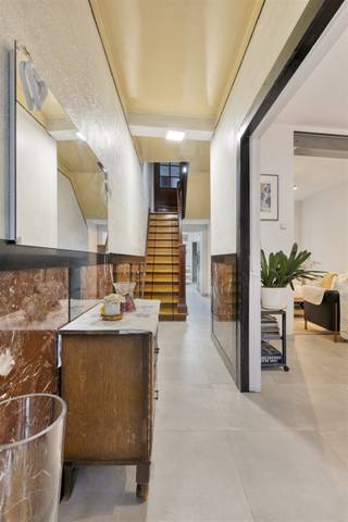 Welkom bij deze gezellige woning in Aalst, dat volledig is getransformeerd tot een moderne familiewoning. Deze woning combineert authentieke details met eigentijdse comfort op een habitable oppervlakte van 161,5 vierkante meter. Deze woning beschikt over vier ruime slaapkamers die perfect geschikt zijn voor gezinnen of voor wie extra ruimte wil. De slaapkamers variëren in grootte en karakter, met enkele kamers voorzien van zolderramen die veel natuurlijk licht binnenbrengen. De gezellige woonruimte nodigt uit tot ontspanning en samenzijn. Met moderne inrichtingen en warme afwerkingen creëert deze woning een uitnodigende sfeer. De open keuken is voorzien van moderne apparatuur en praktische opbergruimte, perfect voor het bereiden van maaltijden en het delen van momenten met naasten. De badkamer is functioneel ingericht met alle nodige voorzieningen. Daarnaast biedt de woning praktische extra ruimtes, waaronder een wasruimte en een werkruimte, ideaal voor thuiswerkenden. Een van de grote voordelen van deze woning is de prachtige buitenruimte. De tuin is voorzien van een lounge-achtig zitgedeelte onder een aangename pergola, perfect voor ontspanning en buiten genieten. De interne indeling is verzorgd met ruimtelijke doorgangen en een aangename circulatie op verschillende niveaus. De trap connecteert alle verdiepingen op elegante wijze, terwijl ramen en daklichten zorgen voor veel daglicht. Deze woning is ideaal voor wie een unieke combinatie zoekt van karakter, moderne voorzieningen en praktische ruimte in het hart van Aalst.