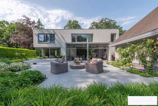 <div>
<div>
<section>
<div>
<div>
<div>
<div>
<div>
<div>
<h2>Exclusive Architect-Designed Villa in a Prime Location in De Lint Residential Estate</h2>
<p>Set on a beautiful southwest-facing plot within walking distance of the unique De Liereman nature reserve, this contemporary architect-designed villa offers an exceptional blend of timeless architecture, generous living spaces and high-quality finishes. Ideally located, both Eindhoven and Antwerp are only approximately 25 minutes away.</p>
<p>Upon entering, you are welcomed by a spacious entrance hall with cloakroom and guest toilet. Elegant double doors lead to the impressive living room, where large windows frame panoramic views of the beautifully landscaped garden. The abundance of natural light and seamless connection with the outdoors create a truly exceptional living experience. Adjacent to the living area is an open space, ideal as a home office.</p>
<p>A stylish double-sided fireplace elegantly connects the living room with the spacious kitchen-diner. The kitchen is impeccably maintained and features quality appliances. Large sliding doors provide direct access to the terraces and garden. A practical utility room and separate laundry room are located behind the kitchen. The ground floor is further complemented by an integrated double garage with automatic door and passenger lift.</p>
<p>Upstairs, the generous landing leads to the impressive master suite with walk-in dressing room and luxurious bathroom. Two additional full-sized bedrooms share a bathroom, while a spacious study can easily be converted into a fourth bedroom and benefits from its own private terrace.</p>
<p>Outside, the mature, fully enclosed garden offers complete privacy and sun terraces and a covered terrace invite you to enjoy outdoor living. An additional detached garage building provides ample space for extra vehicles.</p>
<p>The villa is also exceptionally low-maintenance thanks to its durable aluminium window frames and high-quality brick façades, eliminating the need for exterior painting while preserving its elegant appearance.</p>
<h3>Key Features</h3>
<ul>
<li>Southwest-facing plot with optimal sun exposure</li>
<li>Passenger lift to the first floor</li>
<li>Floor heating on both ground and first floors</li>
<li>Integrated double garage with automatic door</li>
<li>Detached garage building with storage loft</li>
<li>Alarm system</li>
<li>Exterior sun screens</li>
<li>Beautifully landscaped, fully enclosed garden</li>
<li>Large terraces and a covered, heated terrace</li>
</ul>
</div>
</div>
</div>
</div>
</div>
</div>
</section>
</div>
</div>