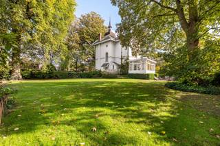 <h1><span>Karaktervolle villa met torentje en ruime tuin in Kapellen</span></h1>
<p><span>In de Eikendreef in Kapellen bevindt zich deze karaktervolle woning uit 1880. De villa ligt in een rustige, groene omgeving en onderscheidt zich door haar typische architectuur, met een torentje, geschilderde bakstenen gevels en karakteristieke dakpartijen.</span></p>
<p><span>De woning werd opgetrokken in cottagestijl, een bouwstijl die herkenbaar is aan de combinatie van verschillende dakvormen en decoratieve details. Het torentje geeft de woning een eigen uitstraling. Ook de gevels en de overige architecturale elementen verwijzen naar de bouwstijl van die periode.</span></p>
<p><span>Binnen beschikt de woning over vijf slaapkamers en twee badkamers. De verschillende ruimtes bieden mogelijkheden voor een gezin dat op zoek is naar een woning met karakter en voldoende plaats. Afhankelijk van de wensen van de toekomstige eigenaar kan de indeling verder worden aangepast. De woning is opgenomen als bouwkundig erfgoed. Afhankelijk van het toepasselijke erfgoedstatuut en de wettelijke voorwaarden kan een vrijstelling van de Vlaamse renovatieverplichting gelden.</span></p>
<p><span>De woning beschikt over een ruime tuin die volop mogelijkheden biedt om buiten te genieten. De groene omgeving en de rustige ligging maken dit tot een aangename plek om te wonen.</span></p>
<p><span>Achteraan op het perceel bevindt zich bovendien een afzonderlijke conciërgewoning van ca. 120 m², met een ruime garage. Het gebouw dient te worden gerenoveerd, maar biedt verschillende mogelijkheden, zoals een kangoeroewoning, gastenverblijf, kantoor of praktijkruimte.</span></p>
<p><span>Een woning met een eigen bouwkundige uitstraling, een ruime tuin en een bijkomend gebouw dat mogelijkheden biedt voor wie op zoek is naar extra ruimte.</span></p>