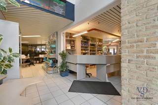 Dit bijzonder ruime en tijdloze pand biedt de unieke mogelijkheid om wonen en werken te combineren in een aangename, stijlvolle omgeving.<br /><br />Bij het betreden van het gebouw komt u terecht in een statige inkomhal die rechtstreeks aansluit op de balie en doorloopt naar de toonzaal en verkoopruimte. Deze open en representatieve zone vormt het kloppend hart van het gelijkvloers en creëert een professionele eerste indruk voor bezoekers en klanten.<br /><br />Verder zijn er meerdere afzonderlijke burelen voorzien, waaronder één kantoor met uitzicht op de achtergelegen vijver – een rustgevende plek die werken in een kalme, groene omgeving mogelijk maakt. Daarnaast is er een open landschapskantoor, een praktische kitchenette, een apart toilet en meerdere bergruimtes - werkruimtes aanwezig.<br /><br />Ook een les- of vergaderruimte maakt deel uit van het gelijkvloers, wat het pand uitermate geschikt maakt voor opleidingen, workshops of teamvergaderingen. Aan de zijkanten (links en rechts) bevinden zich in totaal vier garages, die samen met de parkeermogelijkheden aan de voorzijde én achterzijde van het gebouw zorgen voor een uitstekende bereikbaarheid. Ook een kelder is voorzien. <br /><br />Op de verdieping bevindt zich een riant penthouse waar het woongedeelte volledig tot zijn recht komt. Hier vindt u een ruime leefruimte, een uitgeruste keuken, vier comfortabele slaapkamers en een stijlvolle badkamer.<br />Als kers op de taart is er een wellnessruimte met spa-hoek en sauna, perfect om na een drukke werkdag volledig tot rust te komen. Zowel aan de voorzijde als aan de achterzijde van het gebouw bevinden zich ruime terrassen, ideaal om te genieten van de zon of het uitzicht op de tuin met vijver.<br /><br />Ook op de bovenverdieping is er meer dan voldoende bergruimte, dankzij de aanwezigheid van een atelier, een praktische opslagruimte en zolders aan beide kanten van het gebouw.<br /><br />De tuin is voorzien van o.a. een sierlijke vijver, een recente buitenberging met overkapping en carports voor meerdere wagens. De combinatie van functionaliteit, rust en ruimte maakt van dit pand een echte buitenkans.<br /><br />Bent u op zoek naar een ruim, veelzijdig eigendom waar wonen en werken in perfecte harmonie samengaan? Dan is dit pand precies wat u zoekt.