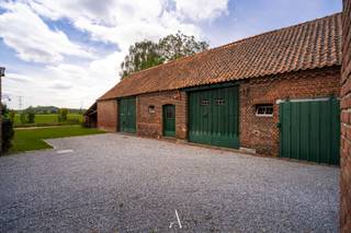 <span>In een uitzonderlijk rustige en landelijke omgeving, volledig omgeven door weilanden, bevindt zich deze unieke hoeve-eigendom met tal van mogelijkheden. Het perceel zal na opmeting door de landmeter een oppervlakte hebben van circa 2.323 m² en omvat drie afzonderlijke gebouwen: een authentieke langegevelhoeve, een vrijstaande woning en een riant garagegebouw.<br /><br />De grootste troeven van deze eigendom zijn zonder twijfel de prachtige ligging met blijvende vergezichten over het omliggende landschap, de aanwezige volumes en het unieke karakter van de historische hoeve.<br /><br /><strong>Authentieke langegevelhoeve</strong><br />De karaktervolle langegevelhoeve dateert van 1921 en staat opgenomen op de inventaris van vastgesteld bouwkundig erfgoed. Met een lengte van ca. 33 meter en een breedte van ca. 8 meter beschikt dit gebouw over indrukwekkende volumes en een authentieke uitstraling. De aanwezige eiken dakconstructie en het historische karakter bieden een uitzonderlijke basis voor een renovatieproject met veel charme en persoonlijkheid.<br /><br />De hoeve is volledig te renoveren, maar biedt tal van mogelijkheden voor wie op zoek is naar een karaktervolle eigendom in een landelijke omgeving.<br /><br /><strong>Woonhuis</strong><br />Het vrijstaande woonhuis werd opgericht in 1955 en beschikt over een bewoonbare oppervlakte van ca. 193 m². De woning is onderhevig aan de renovatieverplichting vanwege het EPC-label F.<br /><br />Op het gelijkvloers omvat de woning een inkomhal met toegang tot de keuken, woonkamer en aparte eetkamer. Aansluitend aan de keuken bevindt zich een sas met achterdeur dat toegang geeft tot de wasruimte, een apart toilet en een technische ruimte met de cv-installatie.<br /><br />Op de eerste verdieping bevinden zich vijf ruime slaapkamers. Eén van deze kamers beschikt over een vaste trap naar de zolderverdieping, die momenteel ingericht is als onafgewerkte bergruimte. Daarnaast is de woning deels onderkelderd en voorzien van twee provisiekelders.<br /><br /><strong>Garagegebouw</strong><br />Het derde gebouw betreft een vrijstaand garagegebouw waarvan vaststaat dat het reeds vóór 1971 werd opgericht. Met een oppervlakte van ongeveer 162 m² biedt dit gebouw tal van mogelijkheden als garage, opslagruimte, werkplaats of hobbyruimte.<br /><br /><strong>Karakter & mogelijkheden</strong><br />De combinatie van een authentieke erfgoedhoeve, een afzonderlijke woning, een groot garagegebouw en een uitzonderlijke landelijke ligging maakt dit een bijzonder veelzijdige eigendom. Een unieke opportuniteit voor liefhebbers van karaktervolle gebouwen, renovatieprojecten en wonen in het groen, met blijvend uitzicht over de omliggende weilanden.<br /><br /><strong>Belangrijke informatie</strong><br />De eigendom is gelegen in agrarisch gebied en heeft bijgevolg een zonevreemd karakter. Kandidaten worden aangeraden zich vooraf grondig te informeren over de stedenbouwkundige mogelijkheden en beperkingen die van toepassing kunnen zijn op zonevreemde woningen.<br />Meer informatie hierover is beschikbaar via: https://omgeving.vlaanderen.be/nl/woning-zonevreemd<br /><br />Daarnaast is de authentieke langegevelhoeve opgenomen op de inventaris van vastgesteld bouwkundig erfgoed. Dit betekent niet dat het gebouw beschermd is als monument, maar bepaalde erfgoedwaarden worden wel erkend en kunnen een rol spelen bij toekomstige renovatie- of verbouwingswerken.<br />Meer informatie hierover is beschikbaar via:</span>
<ul>
<li><span>Inventarisfiche van de hoeve: https://inventaris.onroerenderfgoed.be/erfgoedobjecten/71916 </span></li>
<li><span>Renoveren van een gebouw op een vastgestelde inventaris (Onroerend Erfgoed): https://www.onroerenderfgoed.be/het-goed-staat-een-vastgestelde-inventaris</span></li>
</ul>
<span> Kandidaten die specifieke plannen hebben met de eigendom wordt aangeraden om zich voorafgaandelijk te laten adviseren door een architect, stedenbouwkundig deskundige of de bevoegde overheidsdiensten.</span><br />
