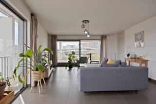 <strong>Hoekappartement met twee slaapkamers en ruim zonneterras.</strong><br /><br />Op de vijfde verdieping bevindt zich dit ruime en lichtrijke appartement met een aangenaam open gevoel.<br /><br />Het appartement beschikt over twee volwaardige slaapkamers, waarvan één slaapkamer is voorzien van een eigen douchekamer en terras met uitzicht op groen en water. In de nachthal bevindt zich bovendien een tweede, volwaardige badkamer.<br /><br />De lichtrijke leefruimte sluit aan op een ruim, zuidgericht terras. Een praktische berging in het appartement zorgt voor extra opbergruimte.<br /><br />Daarnaast beschikt het appartement over een private kelderberging en is er een gemeenschappelijke fietsenberging. Er is tevens de mogelijkheid om een ondergrondse autostaanplaats aan te kopen (€ 30.000).<br /><br />De ligging vormt een extra troef: vlot bereikbaar via de nabijgelegen invalswegen en uitstekend verbonden met de fietsostrade.