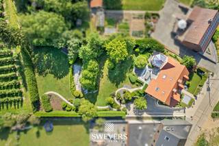Voor meer info en foto’s, surf naar www.swevers.be – In de Groenstraat 42A in Glabbeek wacht deze uitstekend onderhouden villa uit 2003 op een nieuw gezin. Met een bewoonbare oppervlakte van 303 m² en een perceel van 22a 96ca biedt deze woning een zee aan ruimte en comfort. Doorheen de jaren werden diverse verbeteringen uitgevoerd, waaronder airconditioning, maatwerkkasten en een frisse schilderbeurt. De lichtrijke woonkamer van bijna 50 m² sluit aan op een gezellige veranda, terwijl de ruime keuken met kookeiland en praktische bijkeuken ideaal is voor het gezinsleven. Op het gelijkvloers bevinden zich verder een badkamer, bureau, gastentoilet, berging en een inpandige garage voor 2 à 3 wagens. De eerste verdieping telt drie ruime slaapkamers, een badkamer en twee dressings. De volledig afgewerkte zolder is ingericht als twee extra slaapkamers, waardoor de woning in totaal over vijf slaapkamers beschikt, maar kan ook perfect dienen als hobbyruimte of bureau. De volledige onderkeldering van 97 m² biedt tal van mogelijkheden voor opslag, werkplaats of hobbyruimte. Buiten geniet u van een verzorgde tuin met terrassen, petanquebaan en ruime grasvelden. Extra comfort wordt verzekerd door airconditioning, een alarmsysteem, elektrische garagepoorten en elektrische rolluiken. De rustige ligging combineert een vlotte bereikbaarheid met winkels, scholen, openbaar vervoer en de E40 en E314 in de nabije omgeving. Een instapklare en bijzonder complete villa waar ruimte, comfort en functionaliteit perfect samenkomen. Voor meer informatie, bel 011 255 155. Bron bewoonbare oppervlakte: EPC – verslag.