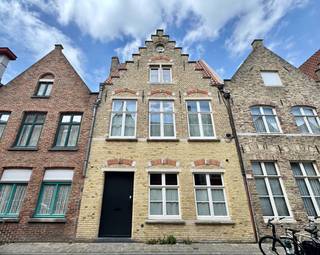 In het gegeerde Guido Gezellekwartier, vlak bij het Engels Klooster, bevindt zich deze charmante en authentieke herenwoning met gezellige stadstuin. Een unieke kans om te wonen op een rustige en mooie locatie, op wandelafstand van de Brugse Vesten en in de onmiddellijke nabijheid van winkels, scholen en openbaar vervoer.
Indeling: ruime inkomhal met ingebouwde kasten en gastentoilet. De prachtige landelijke leefkeuken sluit naadloos aan op de bijzonder ruime leefruimte, ingedeeld in een eetplaats, leeshoek en gezellige zithoek. Dankzij de grote raampartijen geniet deze ruimte van een overvloedige lichtinval en een aangenaam zicht op de stadstuin, die bovendien rechtstreeks toegankelijk is vanuit de leefruimte. De leefruimte wordt extra gekenmerkt door een prachtige parketvloer en een sfeervolle houtkachel.
Op de eerste verdieping bevinden zich twee ruime slaapkamers, waarvan één met dressing, een stijlvolle badkamer uitgerust met een dubbel lavabomeubel, ligbad en inloopdouche, een afzonderlijk toilet en een ruime, praktische wasplaats/berging.
De tweede verdieping, gelegen onder het authentieke gebinte, biedt plaats aan een polyvalente ruimte, een extra slaapkamer met aansluitende dressing en een voorziene ruimte voor een tweede badkamer. De nodige aansluitingen en leidingen zijn reeds aanwezig.
Daarnaast beschikt de woning over een conforme elektrische installatie, een gunstig EPC van 112 kWh/m² (energielabel B), zonnepanelen en airco in de slaapkamers.
Laat u verrassen door de charme, het ruimtegevoel en de centrale ligging van deze unieke stadswoning. 

