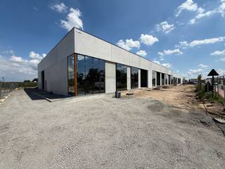 Ruime KMO-unit of showroom van 276 m² met 2 eigen parkeerplaatsen. Deze unit is ideaal voor bedrijven die een zichtlocatie zoeken om hun onderneming te profileren. Gelegen in Dentergem, centraal in de driehoek Tielt-Deinze-Waregem, profiteert deze locatie van een uitstekende bereikbaarheid en visibiliteit. Het magazijn heeft een vrije hoogte van 6 meter en beschikt over kwaliteitsvolle voorzieningen, zoals een lichtstraat met RWA-koepel en grote raampartijen, wat niet alleen de werkruimte aangenaam maakt, maar ook een perfecte gelegenheid biedt om een mezzanine in te bouwen voor extra kantoor- of showroomruimte.<br /><br />De unit wordt casco opgeleverd en maakt deel uit van de vierde fase van de prestigieuze<strong> KMO-ontwikkeling "RIVA."</strong> Deze nieuwe ontwikkeling omvat vier fasen en in totaal 26 units/showrooms, met oppervlaktes van 200 m² tot 373 m², en biedt mogelijkheden tot samenvoeging voor een ruimte van maar liefst 1.850 m². De loodsen zijn perfect geschikt voor uiteenlopende activiteiten, van opslag en productie tot commerciële toepassingen, waardoor ondernemers veel flexibiliteit hebben.<br /><br />Er is verder ook een mogelijkheid om in overleg zonnepanelen of laadpalen te plaatsen. Voor iedere unit zijn <strong>privatieve parkeerplaatsen</strong> voorzien, wat handig is voor zowel personeel als bezoekers.<br />Contacteer <strong>PANORAMA B2B</strong> voor gedetailleerde informatie, bouwplannen, of om een vrijblijvend bezoek te plannen via het nummer <strong>0477 02 09 02</strong>.