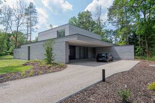 Diep verscholen in het groen, aan het einde van een discrete oprit, bevindt zich deze uitzonderlijke nieuwbouwvilla op een riant perceel van ca. 3.000 m². Dit architecturaal meesterwerk onderscheidt zich door zijn pure vormgeving, zeldzame rust en hoogwaardige materiaalkeuze — een toonbeeld van hedendaagse luxe, zonder in te boeten op warmte of leefbaarheid.<br /><br />De villa werd opgetrokken in een horizontaal metselverband met lichte, genuanceerde gevelsteen. De strakke volumewerking wordt verzacht door de overvloedige glaspartijen die van vloer tot plafond reiken. Ze zorgen niet alleen voor een adembenemende lichtinval, maar creëren ook een naadloze connectie tussen binnen en buiten. De tuin met vijver én zwembad zorgen voor verkoeling op warme dagen.<br /><br />Via de inkomhal betreed je de royale leefruimte met aangename plafondhoogte. De open leefkeuken — op maat ontworpen en voorzien van alle denkbare high-end toestellen — sluit naadloos aan op de living. Grote schuiframen openen naar het zonneterras en het strak geïntegreerde zwembad, ideaal georiënteerd op het zuiden.<br /><br />Op het gelijkvloers vinden we verder nog een gastentoilet, berging, technische ruimte en inpandige fietsenstalling — subtiel ingewerkt in de structuur van het gebouw.<br /><br />De verdieping omvat:<br /><br />- een royale slaapkamer met dressing en ensuite badkamer (inloopdouche, dubbele wastafel, vrijstaand bad)<br /><br />- twee ruime kinderkamers met ingebouwde kasten<br /><br />- een tweede badkamer en apart toilet<br /><br />Elke ruimte ademt rust, licht en verfijning.<br /><br />De villa is bovendien discreet gelegen in een doodlopende straat. Hier geniet u absolute rust en privacy in een groene oase, op wandelafstand van de prestigieuze Golf Club Keerbergen. De combinatie van deze topligging en het unieke architecturale concept maken deze eigendom ronduit zeldzaam.<br /><br />Een huis dat niet enkel ontworpen is om in te wonen, maar om in te leven.