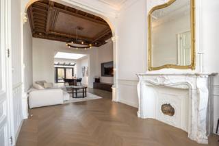 Dit gelijkvloers appartement bevindt zich in een herenhuis, opgedeeld in 4 units. Privé entree met marmer, twee prachtige ruimtes met hoge plafonds, originele plafonds en schouw. Vooraan mogelijks ontvangstruimte of bureau. Middenplaats momenteel ruim salon. Achteraan volwaardig geïnstalleerde keuken met eetplaats, aansluitend het terras. Verder op het gelijkvloers ruime master bedroom met badkamer. Op de eerste verdieping bevinden zich nog een grote en een kleine slaapkamer met badkamer. Wasplaats.
