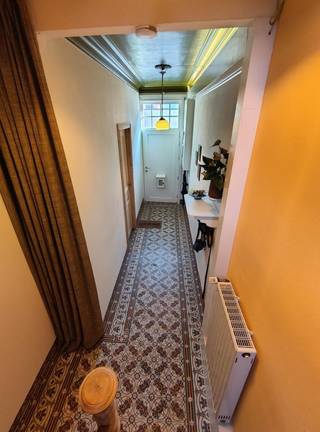 Op zoek naar een woning waar ruimte een troef is? Deze karaktervolle stadswoning van maar liefst 302 m² ligt in het hart van Ieper én op 2 minuten van de vestingen. Met 5 grote slaapkamers, een zonnige zuidgerichte tuin én twee afzonderlijke toegangen en trappenhallen, biedt deze woning bijzonder veel mogelijkheden.
De woning is ideaal voor een gezin dat graag over veel leef-en slaapruimte beschikt, maar ook voor wie thuis wil werken, een hobbyruimte nodig heeft, gasten wil ontvangen, een kangoeroewoning wil ontwerpen...
Op het gelijkvloers bevinden zich een inkomhal, een ruime en lichtrijke leefruimte, keuken, bureau, berging en fietsenberging. Vanuit de leefruimte kom je in de ommuurde, zuidgerichte tuin.
Op de eerste verdieping zijn er drie slaapkamers en een badkamer. De tweede verdieping telt nog twee slaapkamers en twee zolderruimtes, die extra mogelijkheden bieden.
Bij de verbouwing bleven verschillende authentieke elementen behouden, zoals oude deuren, charmante tegels en de mooie houten trappen. De woning beschikt over 38 m² zuidgerichte zonnepanelen (6.000 Wp) en een thuisbatterij, en groenestroomcertificaten.
Vooraan is er momenteel een ruime garage-/bergruimte voor fietsen, materiaal en opslag. Onder de woning bevinden zich twee kelderruimtes van samen ongeveer 44 m², voornamelijk geschikt voor opslag.
De woning is perfect bewoonbaar, en biedt tegelijk de mogelijkheid om bepaalde onderdelen naar eigen smaak af te werken: zo vertoont de vloer in de woonruimte gebruikssporen en kan de tweede trappenhal naar eigen wens worden afgewerkt.
Na 25 jaar met veel plezier in deze woning te hebben gewoond, verkopen we ze rechtstreeks als eigenaars. We tonen de woning zoals ze werkelijk is: de foto's zijn niet bewerkt met AI of verbloemende filters. Tijdens een bezoek vertellen we graag eerlijk over zowel de sterke punten als de minder praktische kanten van de woning.
Interesse? Neem gerust contact op via lombaardstraat41@tuta.com of 0496/971482 (Barbara Decramer).