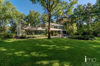 Instapklare high-end villa in meer- en golfomgeving.<br /><br />Deze modernistische woning met unieke invulling biedt alle comfort en rust in een oase van groen en bos.<br /><br />Bij het betreden van dit pand worden we meteen verbaasd door de dakramen naast de woonkamer en de aandacht voor bijzondere, exclusieve materialen. De leefruimte is voorzien van een mooie gashaard en wordt door een kastenwand gescheiden van de bureau-ruimte. Aansluitend is er een eetplaats met geweldige wijnkast, alsook een volledig uitgeruste keuken met speciale kookapparatuur.<br /><br />Naadloos weggewerkt in de keukenwand vinden we een deur die toegang biedt tot de gelijkvloerse slaapkamer met eigen badkamer, de berging en wasplaats met koelcel en gelijkvloerse staanplaats voor de wagen.<br />De woning biedt alle moderne comfort en werd uitgerust met de nieuwste technieken waaronder alle voorbereidingen om een lift te kunnen installeren. Door de gebruikte technieken is de woning natuurlijk ook energiezuinig. (E50)<br /><br />Op de eerste verdieping vinden we een ruime master-bedroom met eigen haard die 180° zicht biedt over de aangelegde tuin. Hierbij werd zowel een bad als douche voorzien met op het dakterras tevens een stoomcabine en whirlpool. Naast de badkamer vinden we een inloopdressing met indirecte verlichting en lichtkoepel voor overdag.<br /><br />Behalve het bijzondere leefconcept met rijkelijke lichtinval overal op de bovengrondse verdiepingen, heeft de woning nog een ruime kelder dewelke langs binnen en met een autolift langs buiten toegankelijk is. Deze ruimte van 350 m2 kan aangewend worden tot een enorm atelier of een bijzondere stalplaats voor een prachtige autocollectie. Andere invullingen zijn natuurlijk ook mogelijk gezien er natuurlijk licht binnenvalt en er ook op de ondergrondse verdieping ramen voorzien zijn.<br /><br />Bekijk ook zeker onze website voor de interactieve grondplannen.<br />Meer info via Jean.Heylen@imovastgoed.be of via 015/34.34.54.