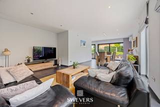Voor meer info en foto’s, surf naar www.swevers.be – Deze instapklare open bebouwing aan de Schutenseweg 95 in Zonhoven biedt maar liefst 267 m² woonoppervlakte op een perceel van 10a54. De woning uit 2005 combineert ruimte, comfort en veelzijdigheid, ideaal voor grote gezinnen, zorgwoning of wie wonen en werken wil combineren.<br />Via de imposante inkomhal bereikt u de lichtrijke leefruimte van 41 m² met grote raampartijen en directe toegang tot de tuin. Aansluitend bevindt zich een afzonderlijk bureau dat eenvoudig opnieuw bij de woonkamer kan worden betrokken. De ruime leefkeuken van 22 m² beschikt over alle nodige inbouwtoestellen, veel bergruimte en plaats voor een grote eettafel. Verder zijn er op het gelijkvloers een wasplaats met maatkasten, een extra douche en een praktische vestiaire. Een grote troef is de voormalige inpandige garage die werd ingericht als praktijk- of hobbyruimte van circa 34 m² met eigen ingang. Deze ruimte biedt tal van mogelijkheden als kantoor, atelier, zorgunit of logeerverblijf. Op de verdieping bevinden zich vier slaapkamers, waaronder een masterbedroom met his-and-her inloopdressing. De vernieuwde badkamer is uitgerust met een ruime dubbele inloopdouche, dubbele lavabo en maatkasten. Daarnaast is er een afzonderlijk toilet aanwezig. De woning is volledig onderkelderd met ongeveer 60 m² extra bergruimte en beschikt bovendien over een zolder van circa 60 m² met uitbreidingsmogelijkheden. Buiten geniet u van een verzorgde tuin met terras, fruitbomen, bessenstruiken en fietsenstalling. Extra comfort wordt geboden door airco’s, zonnepanelen met thuisbatterij en een laadpaal voor elektrische voertuigen. De rustige ligging combineert een vlotte bereikbaarheid met scholen, openbaar vervoer, winkels, Hasselt en de autosnelweg in de nabije omgeving. Voor meer informatie, bel 011 255 155. Bron bewoonbare oppervlakte: EPC – verslag.