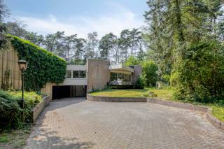 <p>Deze bijzondere architectenvilla uit 1977 is gelegen op een prachtig perceel van ca. 9.820 m² in het groene Kapellen. Dankzij de opvallende stervormige bouwstijl, de grote raampartijen en de doordachte indeling geniet u hier van een woning waar licht, ruimte en natuur centraal staan. De villa beschikt over een royale leefruimte, een vernieuwde keuken, vijf slaapkamers en tal van polyvalente ruimtes, waardoor deze woning perfect geschikt is voor een groot gezin of voor wie wonen en werken wenst te combineren.<br /><br /><strong>Indeling:</strong><br />Via de inkomhal op betreedt u de woning. Hier bevindt zich een centrale ronde ontvangstruimte die toegang geeft tot verschillende polyvalente ruimtes. Deze ruimtes kunnen perfect ingericht worden als kantoor, praktijkruimte, hobbyruimte of extra bergruimte. Verder beschikt dit niveau over een wellnessruimte met sauna en een inpandige garage.</p>
<p>Op de tuinverdieping wordt u verwelkomd in de indrukwekkende centrale hal met een groene marmeren vloer en een grote lichtkoepel, die zorgt voor een aangename lichtinval. De ruime leefruimte op parket geniet dankzij de grote schuiframen van een prachtig zicht op de tuin. Aansluitend bevindt zich de volledig vernieuwde keuken, uitgerust met kwalitatieve toestellen en voldoende werk- en opbergruimte. Achter de keuken bevindt zich nog een gezellige zithoek, ideaal als tv-hoek of leesruimte.</p>
<p>Verder beschikt de woning over vijf ruime slaapkamers voorzien van ingemaakte kasten. De master bedroom beschikt over een privatief terras en een ruime en suite badkamer met ligbad, douche, dubbele lavabo en toilet. Daarnaast zijn er nog twee bijkomende badkamers, waardoor deze villa ook perfect geschikt is voor grote gezinnen of wie graag gasten ontvangt.</p>
<p><strong>Buitenruimtes:</strong><br />De villa bevindt zich op een prachtig perceel van ca. 9.820 m², omringd door een parkachtige tuin met een vijver en veel bomen. Dankzij de volledige privacy geniet u hier het hele jaar door van rust en een unieke groene omgeving. <br /><br /><strong>Bijzonderheden:</strong><br />Unieke architectenvilla uit 1977.<br />Vernieuwde keuken.<br />Ruime leefruimte op parket met open haard.<br />Polyvalente ruimtes, ideaal voor een vrij beroep of zelfstandige activiteit.<br />Elektrische keuring conform.<br />EPC-label F.<br /><br /><strong>Ligging:</strong><br />De woning is rustig gelegen in Kapellen vlakbij winkels, scholen, horecazaken en het station. Een unieke locatie voor wie op zoek is naar ruimte, privacy en een groene woonomgeving.<br /><br /><strong>Renovatieplicht:</strong><br />Deze woning valt onder de renovatieverplichting. Sinds 2023 moet een nieuwe eigenaar, opstalhouder of erfpachter binnen 6 jaar een woning met een slecht EPC-label energetisch renoveren tot minimaal label D.</p>