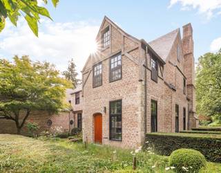 <p>Verscholen tussen eeuwenoude bomen aan één van de gegeerde dreven in Schilde ligt deze indrukwekkende villa die pure klasse, ruimte en privacy ademt. <br />De baksteengevel met glooiende leien daken, sierlijke schoorstenen en vakwerkdetails in combinatie met een kasseien oprit, omzoomd door strak geschoren hagen, een zeldzame combinatie van authentieke allure en hedendaags comfort.</p>
<p>De inkomhal met blauwe natuursteen vormt het hart van de woning en geeft toegang tot de verschillende woonvertrekken. <br />De lichte woonkamer met gashaard vloeit naadloos over in de eetkamer en de ruime keuken, waardoor een prachtige open leefruimte ontstaat met fraai zicht op de tuin. De leefkeuken is uitgewerkt met een eiland afgewerkt met blauwe natuurstenen werkblad. Een professioneel Viking gasfornuis aangevuld met premium toestellen zorgt voor extra comfort. De gashaard creërt warmte en gezelligheid bij het diner. <br />Overal in de villa is hoogwaardig houten maatwerk verwerkt. De vloeren zijn zorgvuldig gekozen: blauwe natuursteen in de inkom en keuken, warm eiken parket in de overige ruimtes. Een wijnkelder maakt het plaatje compleet. Alle leefruimtes zijn voorzien van vloerverwarming en airconditioning.</p>
<p>Op de eerste verdieping geniet u van een royale mastersuite met dressing, slaapgedeelte en een luxe badkamer met inloopdouche, ligbad en dubbele wastafel. Daarnaast vindt u een tweede slaapkamer met eigen badkamer, twee extra slaapkamers en een derde badkamer. Alle slaapkamers zijn uitgerust met airconditioning. <br />De bovenste verdieping herbergt een comfortabel gastenvertrek met eigen badkamer.</p>
<p>Buiten opent zich een weelderige tuin. Achteraan aan het zonneterras grenst een verwarmd zwembad met poolhouse, compleet met wellnessvoorzieningen (sauna, stoombad en douche) en een Silverspa-jacuzzi voor zes personen. Een tweede bijhuis fungeert als sfeervol clubhouse. De grote koivijver vormt een rustgevend middelpunt in de tuin. <br />Twee inpandige garages en ruim voldoende parkeergelegenheid buiten vervolmaken het geheel.<br />Deze villa biedt een exclusieve leefomgeving waar rust, luxe en genieten samenkomen.</p>