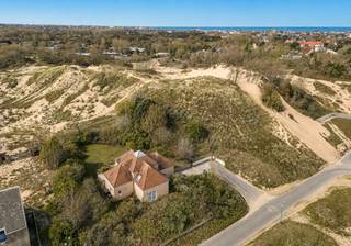 Op een van de meest gegeerde locaties aan de Belgische kust, verscholen in de prestigieuze villawijk Witte Burg, ligt deze uitzonderlijke eigendom. Omringd door duinen, eeuwenoude bomen en een ongekende rust geniet deze villa van een zeldzame combinatie van absolute privacy, natuur en exclusiviteit en dit op wandelafstand van dorpswinkels. <br /><br />Gelegen op een prachtig perceel van 1.755 m² vormt deze karaktervolle villa een unieke plek waar binnen en buiten naadloos in elkaar overvloeien. De woning, gebouwd in 1987, beschikt over een bewoonbare oppervlakte van ongeveer 199 m² en biedt bovendien interessante uitbreidingsmogelijkheden, waardoor ze zich moeiteloos laat aanpassen aan de woonwensen van morgen.<br /><br />De royale inkomhal zet meteen de toon. Lichtrijke leefruimtes met grote raampartijen kijken uit op het omliggende groen en baden de woning de hele dag in natuurlijk licht. Een gezellige tweede salon creëert een intieme plek om te ontspannen, terwijl de afzonderlijke keuken alle mogelijkheden biedt voor een eigentijdse invulling.<br /><br />Op het gelijkvloers bevindt zich tevens een stijlvolle bureauruimte met uitzicht op de tuin en een comfortabele master suite met een recent vernieuwde badkamer en apart toilet. Op de verdieping bevinden zich drie ruime slaapkamers, elk met een eigen badkamer, waardoor familie en gasten in alle comfort en privacy kunnen verblijven.<br /><br />Ook buiten straalt dit eigendom een bijzondere sereniteit uit. De prachtig aangelegde tuin vormt een discreet verlengstuk van het omliggende duinenlandschap en biedt een uitzonderlijk gevoel van vrijheid.<br /><br />Een dubbele garage, een ruime oprit en een praktische ondergrondse wasplaats vervolledigen het comfort van deze villa.<br /><br />Eigendommen op deze locatie worden slechts zelden aangeboden. Deze villa biedt een unieke kans om te wonen op een van de meest exclusieve adressen van Oostduinkerke, waar natuur, discretie en een uitzonderlijke woonkwaliteit samenkomen.<br /><br />Kenmerken<br /><br />Prestigieuze ligging in de residentiële villawijk Witte Burg<br /><br />Perceel van 1.755 m²<br /><br />Bewoonbare oppervlakte ca. 199 m²<br /><br />Mogelijkheid tot uitbreiding<br /><br />4 slaapkamers<br /><br />4 badkamers<br /><br />Bureauruimte<br /><br />Twee leefruimtes<br /><br />Dubbele garage<br /><br />Ondergrondse wasplaats<br /><br />Ruime oprit<br /><br />Terras en prachtig aangelegde tuin<br /><br />P-score: A<br /><br />G-score: A