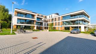 In een nieuwbouwresidentie bevindt zich op de eerste verdieping dit prachtig afgewerkte nieuwbouwappartement. De combinatie van ruimte, veel natuurlijk licht, een hoogwaardige afwerking en een bijzonder groene omgeving maakt dit een zeer aangename plek om thuis te komen.<br /><br />Via de inkomhal bereik je de verschillende ruimtes van het appartement. De ruime en lichtrijke leefruimte geniet dankzij de grote raampartijen van een mooi zicht op het omliggende groen en geeft rechtstreeks toegang tot het ruime terras. Hier geniet je in alle rust van het buitenleven.<br /><br />De open keuken sluit perfect aan bij de leefruimte en is volledig ingericht met kwalitatieve toestellen. Het appartement beschikt over twee volwaardige slaapkamers en twee verzorgde badkamers. Eén badkamer is uitgerust met een ligbad en badkamermeubel, terwijl de tweede badkamer beschikt over een inloopdouche en badkamermeubel. Daarnaast zijn er twee aparte gastentoiletten aanwezig. Een praktische berging met aansluitingen voor wasmachine en droogkast zorgt voor extra comfort en opbergruimte.<br /><br />Ook op vlak van energiezuinigheid scoort dit appartement bijzonder goed. Een warmtepomp en ventilatiesysteem D zorgen voor hedendaags wooncomfort en een laag energieverbruik.<br /><br />Extra troeven zijn de privékelderberging en autostaanplaats. De residentie beschikt over een lift en is modern en verzorgd afgewerkt.<br /><br />Huurprijs: € 1.500/maand<br />Gemeenschappelijke lasten: € 100/maand<br />Onmiddellijk beschikbaar<br /><br />Wie op zoek is naar een ruim, modern en energiezuinig appartement met twee slaapkamers, twee badkamers, een groot terras, veel licht en een groene, rustige ligging, vindt hier een uitzonderlijk complete woonst.<br /><br />Neem contact op met Woonbureau voor meer informatie of een bezoek.
