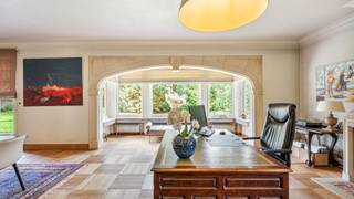 Verscholen op een prachtig perceel van maar liefst 35a 89ca ligt deze unieke villa, een eigendom die zich moeilijk laat vergelijken met het klassieke woningaanbod. Achter de poort ontvouwt zich een domein waar authentieke architectuur, royale volumes en een groene, volledig privatieve tuin naadloos in elkaar overvloeien. <br /><br />De villa werd in 1978 gebouwd door een aannemer die koos voor duurzame materialen en verfijnd vakmanschap. Vandaag is die kwaliteit nog steeds zichtbaar in de talrijke authentieke elementen die de woning haar ziel geven. Franse zandstenen bogen, een karaktervolle erker, massief eiken deuren, elegante trappen en warme parketvloeren zorgen voor een tijdloze uitstraling die doorheen de jaren met zorg werd behouden. <br /><br />Bij het binnenkomen in de hoofdwoning wordt u verwelkomd in een ruime inkomhal waar de indrukwekkende Franse zandstenen bogen meteen de toon zetten. De authentieke materialen en het rijke eiken schrijnwerk creëren een sfeer van klasse en warmte. Vanuit de inkomhal vloeit de woning verder naar de verschillende leefruimtes, bestaande uit een sfeervolle woonkamer, een gezellige eetkamer en een ruime keuken waar het dagelijkse leven zich ongetwijfeld afspeelt. Daarnaast beschikt het gelijkvloers over een bureau, ideaal voor thuiswerk of een vrij beroep, een praktische bijkeuken en extra bergruimte. <br /><br />Op de verdieping bevinden zich drie ruime slaapkamers en een badkamer. Via een zolderluik bereikt u de geïsoleerde zolder, die perfect dienst doet als extra opslagruimte. Ondergronds beschikt de woning bovendien over een kelder, wijnkelder en kruipkelder. <br /><br />Doorheen de woning zorgen de combinatie van natuursteen, massief eikenhout en parketvloeren voor een bijzonder warme sfeer. Hier voelt elke ruimte authentiek aan, zonder in te boeten aan comfort. <br /><br />Een absolute meerwaarde van deze eigendom is de volledig geïntegreerde tweede woongelegenheid. Via een charmante overdekte boogverbinding staat deze zelfstandig woonunit in contact met de hoofdwoning, terwijl beide delen toch hun eigen privacy behouden. <br /><br />Deze tweede woongelegenheid werd de afgelopen jaren grondig gemoderniseerd en straalt hedendaagse klasse uit. De lichtrijke leefruimte met open keuken vormt het centrale hart van de woning. De maatwerkkeuken met royaal kookeiland, geïntegreerde toestellen en uitgebreide kastruimte werd ontworpen met oog voor functionaliteit en esthetiek. Een elegante metalen wenteltrap leidt naar de verdieping, waar een ruime slaapkamer met ingebouwde kastenwand en een comfortabele badkamer met ligbad en aparte douche werden ingericht. <br /><br />Ook buiten onderscheidt deze eigendom zich moeiteloos. De prachtig onderhouden tuin biedt een uitzonderlijk gevoel van rust en privacy. Volwassen beplanting, uitgestrekte groenzones en verschillende terrassen zorgen ervoor dat u op elk moment van de dag een aangename plek in de zon of schaduw vindt. <br /><br />De tweede woongelegenheid beschikt over een eigen terras met zonneluifel en een afzonderlijke tuinzone. Beide tuingedeeltes worden op een sfeervolle manier met elkaar verbonden via een fontein, waardoor het geheel aanvoelt als een harmonieus privépark. <br /><br />Deze eigendom biedt een zeldzame combinatie van authentieke charme, kwalitatieve afwerking, uitzonderlijke oppervlakte en flexibele woonmogelijkheden. Een ideale thuis voor grote gezinnen, kangoeroewonen, zorgwonen of wie wonen en werken wenst te combineren in een unieke en stijlvolle omgeving.