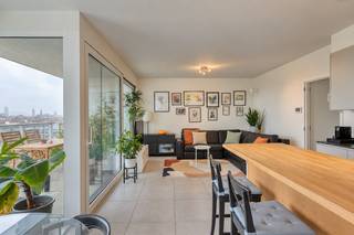Op de zesde verdieping van De Faar, in de duurzame wijk De Nieuwe Dokken, bevindt zich dit luxueuze appartement met drie slaapkamers, twee badkamers en een prachtig uitzicht.<br /><br />De royale leefruimte omvat een ruime open keuken met plaats voor een volwaardige eetkamer en een aansluitende, gezellige televisiehoek. Van hieruit bereikt u het terras, met zijdelings uitzicht op het water en de drie torens van Gent: een bijzonder mooi stedelijk panorama.<br /><br />Het appartement beschikt over drie slaapkamers. De eerste badkamer is uitgerust met een ligbad en toilet; de tweede met een ruime inloopdouche. Daarnaast is er een afzonderlijk gastentoilet en een praktische, ruime berging. <br /><br />De Faar ligt aan het Handelsdok, tussen water en groen en op wandelafstand van de historische binnenstad. Via de Batavia- en Matadibrug bereikt u vlot het centrum. Ook station Gent-Dampoort en de Gentse ring zijn gemakkelijk bereikbaar.<br /><br />Een ondergrondse parkeerplaats kan worden bijgekocht voor € 30.000. Een extra ondergrondse berging is verkrijgbaar voor € 7.500, fietsenstalling is inbegrepen in de prijs.<br /><br />Een uitzonderlijk appartement voor wie ruimte, comfort, duurzaamheid en een uniek uitzicht wil combineren op een van de aantrekkelijkste woonlocaties van Gent.