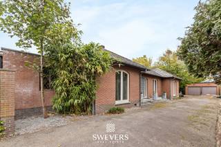 Voor meer info en foto’s, surf naar www.swevers.be – Aan de Hulsbergweg 14 in Zonhoven bevindt zich deze open bebouwing op een ruim perceel van 795 m². De woning werd gebouwd in 1976, heeft een bewoonbare oppervlakte van 180 m² en beschikt over een praktische, volledig gelijkvloerse indeling. Ideaal voor wie op zoek is naar een woning met potentieel die naar eigen smaak kan worden opgefrist. De ruime woonkamer van 44,45 m² biedt voldoende plaats voor een gezellige zit- en eethoek en sluit aan op de veranda met zicht op de tuin. De afzonderlijke keuken van 15,15 m² biedt heel wat mogelijkheden voor een functionele inrichting. Verder zijn er drie slaapkamers van 12 m², 16 m² en 12,25 m². Een bijkomende kamer kan perfect dienstdoen als bureau, hobby- of speelkamer. De badkamer is uitgerust met een bad, wastafel en toilet. Daarnaast is er nog een afzonderlijk toilet aanwezig. Extra opbergruimte vind je in de kelder van 15 m². Een grote troef is de vrijstaande dubbele garage van maar liefst 50 m², ideaal voor wagens, fietsen, tuinmateriaal of een werkhoek. De ruime tuin rondom de woning biedt volop mogelijkheden om van het buitenleven te genieten. Openbaar vervoer en de snelweg bevinden zich bovendien op korte afstand, terwijl scholen, winkels en ontspanning vlot bereikbaar zijn. Voor meer informatie, bel 011 255 155. Bron bewoonbare oppervlakte: EPC – verslag.
