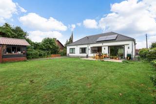 Deze moderne, instapklare en energiezuinige 4 slaapkamer villa (bungalow) op een perceel van maar liefst 12 are 30 ca, gelegen nabij het centrum van Buggenhout, is een tot in de puntjes afgewerkte open bebouwing met alle hedendaags wooncomfort (totaalrenovatie in 2023) en een uitstekende ligging nabij het station. De woning beschikt over een inkomhal met apart toilet,  een open, volledig uitgeruste keuken met berging sluit naadloos aan op de leef-en eetruimte en biedt een mooi zicht op het terras en de tuin. Naast 3 ruime, volwaardige slaapkamers is er ook een kleinere, vierde kamer of bureel. Ideaal voor de combinatie werken-wonen. Het ruime bijgebouw (60 m²) in de tuin kan dienst doen als garage of bergplaats. Dankzij de grote raampartijen geniet de woning van een overvloed aan natuurlijk licht, wat het ruimtegevoel extra versterkt. Naast de badkamer uitgerust met ligbad, dubbele wastafel in een meubel en handdoekdroger is er een tweede badkamer uitgerust met inloopdouche, enkele wastafel in meubel en handdoekdroger aansluitend aan de master bedroom. De oprit, de voortuin, het terras en de tuin maken het plaatje compleet. Deze woning is uitgerust met een warmtepomp, zonnepanelen, PVC schrijnwerk, een elektrische zonneluifel, voorzieningen voor een laadpaal. De centrale ligging in de driehoek Antwerpen–Brussel–Gent zorgt voor een uitstekende bereikbaarheid en maakt deze woning tot een ideale uitvalsbasis. Bovendien scoort de woning bijzonder goed op vlak van energie, met recente technieken die zorgen voor een lage energiefactuur en een gunstig EPC-label. EPC: 213 kWh/m²/j. Energielabel: C, UC: 3016792-RES-1. Voor een bezoek: 052/52.05.05 of axel@ax-quality.be