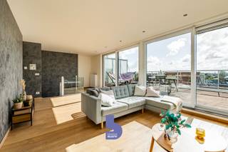 Ruimte, licht en een uitzonderlijk terras op een toplocatie. Dit prachtige duplex penthouse is gelegen op de 4de verdieping van de klassevolle residentie ‘Fusion’, een recente residentie uit 2008. Dankzij de centrale ligging bevinden winkels, openbaar vervoer, het strand en belangrijke invalswegen zich allemaal binnen handbereik.<br /><br />Met maar liefst 133 m² bewoonbare oppervlakte, drie slaapkamers en een riant, zonovergoten terras biedt dit penthouse een uitzonderlijk gevoel van ruimte en comfort.<br /><br />Bij het binnenkomen ervaar je meteen het WOW-effect. De bijzonder lichtrijke woonkamer baadt in het zonlicht en geniet rondom van terrassen, waardoor binnen en buiten hier perfect in elkaar overvloeien.<br /><br />De aangename parketvloer zorgt voor een warme en stijlvolle uitstraling. Er is voldoende ruimte voor een ruime zithoek en een aparte eetruimte, terwijl de grote keuken aansluit op de leefruimte en bovendien beschikt over een extra berging.<br /><br />De nachthal geeft toegang tot drie volwaardige slaapkamers, een badkamer met comfortabele inloopdouche en een apart toilet.<br /><br />Maar de absolute troef van dit penthouse is zonder twijfel het riante terras. Hier geniet je volop van de zon, de openheid en het mooie zicht rondom. Op heldere dagen reikt het zicht zelfs tot aan de zee in de verte. Een heerlijke plek om te ontbijten in de ochtendzon, lang te tafelen met vrienden of simpelweg te genieten van de rust en het uitzicht.<br /><br />De combinatie van de royale bewoonbare oppervlakte, de overvloedige lichtinval, de verschillende terrassen, drie slaapkamers en de uitstekende ligging maakt van dit duplex penthouse een bijzonder aangename woonst. Bovendien geniet je in deze recente residentie van een uitstekend EPC-label B en zijn er een gemeenschappelijke fietsenberging en afvalberging aanwezig.