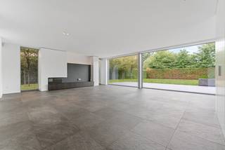 Dans un endroit particulièrement calme et résidentiel à Oud-Turnhout se trouve cette villa moderne, construite en 2014 et située sur un beau terrain de 1 750 m². La villa se distingue par son architecture épurée, ses généreux volumes de vie et son agencement réfléchi et particulièrement fonctionnel. De grandes baies vitrées offrent une abondance de lumière naturelle et renforcent la connexion entre les espaces de vie, les terrasses et le jardin. Avec quatre chambres à coucher complètes, deux salles de bains, un double garage intégré et un sous-sol complet, cette villa offre une sensation d'espace exceptionnelle et tout le confort pour une famille. Des aménagements sur mesure de haute qualité (réalisés par ILB à Kasterlee) parcourent la maison et lui confèrent une allure intemporelle et soignée. Sur le plan énergétique également, la villa convainc avec un label énergétique exceptionnel A et un score énergétique de seulement 94 kWh/m² par an.<br /><br />Rez-de-chaussée :<br />Le spacieux hall d'entrée avec vestiaire et toilettes invités forme une entrée agréable et donne accès aux différents espaces de vie. Au centre de la maison se trouve le généreux salon avec cheminée au gaz, qui, grâce à son agencement ouvert, se connecte parfaitement à la cuisine entièrement équipée. Les grandes baies vitrées offrent une agréable lumière naturelle et offrent une belle connexion avec le jardin et les vastes terrasses qui sont directement accessibles depuis le salon et la cuisine. La cuisine est équipée d'un plan de travail en Corian et d'une table à manger intégrée, et dispose d'un ensemble complet d'appareils électroménagers de qualité, dont une plaque à induction, un four à vapeur haute pression Miele, un four à chaleur tournante Miele, un réfrigérateur et un lave-vaisselle. <br />Adjacent au salon se trouve un espace bureau séparé avec bureau fixe et armoires sur mesure. Un endroit idéal pour le télétravail, l'étude ou un espace de travail paisible. Le rez-de-chaussée comprend également une buanderie spacieuse et pratique, ainsi qu'un garage double intégré avec place pour deux voitures et deux points de charge. Depuis le garage, il y a un accès direct au jardin ainsi qu'au sous-sol.<br /><br />Premier étage :<br />L'escalier depuis le hall d'entrée mène à un hall de nuit spacieux et lumineux. La suite parentale forme une zone privée complète et comprend une grande chambre à coucher, un dressing séparé et une salle de bains privative avec baignoire, douche, double vasque et toilettes. En outre, à cet étage se trouvent trois autres chambres à coucher complètes. Chacune de ces chambres est équipée de placards sur mesure pratiques et d'un bureau intégré, alliant ainsi fonctionnalité et esthétique. Une deuxième salle de bains avec douche et double vasque est à disposition de ces chambres. Le hall de nuit abrite également des toilettes séparées.<br /><br />Sous-sol :<br />Un atout particulier est le sous-sol complet de la villa. Outre une quantité exceptionnelle d'espace de rangement supplémentaire, cet étage offre de nombreuses possibilités pour une utilisation sur mesure, comme un espace hobby, une salle de fitness, une salle de jeux, une cave à vin ou un espace de stockage supplémentaire.<br /><br />Jardin & terrasses :<br />La villa est située sur un grand terrain de 1 750 m² et est entourée d'un vaste jardin qui crée un cadre verdoyant agréable et assure l'intimité nécessaire. L'ensemble est clôturé et équipé d'un portail automatique côté rue. Adjacents au salon et à la cuisine se trouvent de vastes terrasses, permettant ainsi aux espaces de vie de se prolonger naturellement à l'extérieur pendant les mois les plus chauds. La connexion directe entre la cuisine, le salon, les terrasses et le jardin rend l'ensemble particulièrement agréable à la fois pour la vie quotidienne de la famille et pour recevoir des invités.<br /><br />Confort de vie économe en énergie :