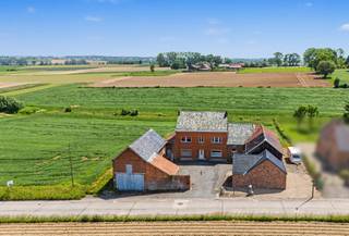 Deze karaktervolle hoeve biedt een unieke combinatie van ruimte, authenticiteit en potentieel. De zeer ruime en solide woning beschikt over een schuur, garage en diverse bijgebouwen. Bovendien omvat het pand een kelder, een volwaardige gelijkvloerse verdieping, een eerste verdieping en een grote zolder, waardoor er tal van mogelijkheden zijn voor uitbreiding en herinrichting.
De woning telt momenteel vier ruime slaapkamers, met de mogelijkheid om bijkomende kamers te creëren op de zolderverdieping. Hoge plafonds, een symmetrische indeling en grote raampartijen zorgen voor een aangename lichtinval en een uitzonderlijk ruimtegevoel. Vanuit vrijwel elke kamer geniet u bovendien van een prachtig uitzicht op het omliggende landschap.
Het perceel heeft een oppervlakte van ongeveer 35 are, onder voorbehoud van opmeting door de landmeter. De ligging combineert landelijke rust met een vlotte bereikbaarheid: een bushalte bevindt zich op wandelafstand en het station ligt op ongeveer 3 km.
Wie geeft deze prachtige hoeve de renovatie die ze verdient en maakt er opnieuw een echte parel van? Contacteer Sophie 0496/71.50.59 voor meer info of afspraak