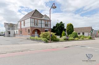 Deze gekende, karaktervolle voormalige directeurswoning situeert zich op een commerciële topligging, waardoor er talrijke mogelijkheden zijn op vlak van wonen en werken. <br />Het gelijkvloers beschikt over een stijlvolle inkom, een ruime leefruimte, keuken, en enige aanhorigheden. Er is eveneens een kelder aanwezig. <br />De verdieping huisvest een ruime badkamer en drie grote slaapkamers. Er is een vaste trap naar de zolderverdieping.<br /><br />Eigendom met mogelijkheden !<br /><br />De woning staat vermeld in de inventaris bouwkundig erfgoed (provincie Oost-Vlaanderen).