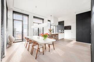 <p>In de skyline van Antwerpen, op ’t Eilandje, bevindt zich deze buitengewone penthouse. Een woning die architecturale ambitie en verfijnde luxe verenigt op een manier die zeldzaam is. <br /><br />De leefruimte strekt zich uit over een indrukwekkende oppervlakte en baadt in natuurlijk licht via kamerhoge raampartijen, met zicht op Antwerpen en het Kattendijkdok. Het hart van de woning is een architecturale blikvanger, een glazen atrium dat buiten naar binnen brengt als een groene oase, waarrond de woonkamer zich vormt.<br />Een ruime eetkamer sluit aan op de open keuken. Het kookeiland is afgewerkt in marmer, een natuursteen die warmte en levendigheid in zich draagt. Volledig geïntegreerde Miele-apparatuur, inclusief stoomoven, mircogolf, oven en koffieapparaat, samen met een Quooker-kraan, maken van koken een verfijnde ervaring.<br />De ingemaakte kastenwand in zwart eik verbindt de ruimtes en voegt een ingetogen luxe toe die diepte en karakter geeft. Van hieruit vloeit de ruimte naadloos over in het salon, waar de ingebouwde open haard subtiel de aandacht trekt.<br />De terrassen rondom de leefruimte en slaapkamers creëren een groene buffer en bieden verschillende plekken om te genieten van zon en stadszichten.<br />De masterbedroom beschikt over een ensuite badkamer afgewerkt met marmer en uitgerust met Vola-kraanwerk, dubbele lavabo, inloopdouche en whirlpoolbad. De kamer is voorzien van airconditioning. De twee extra slaapkamers lenen zich perfect als slaapruimte of thuiswerkplek. Een bijkomende douchekamer, eveneens afgewerkt met Vola-kraanwerk en marmer, zorgt voor extra comfort.<br />De absolute kroon is het zonnige dakterras, omgeven door weelderig groen, met lounge- en eetzone en panoramisch uitzicht over het Eilandje. Een ingebouwde sauna maakt dit terras een plek voor ontspanning in elk seizoen.<br />Bijkomend werd geopteerd voor een PV-installatie van 20 panelen en een thuisbatterij om de energiezuinigheid te verduurzamen. <br />Verder wordt het wooncomfort verhoogd met een afgesloten garagebox, met ruime berging, voor vier wagens in de ondergrondse parkeergarage dewelke aan te kopen is voor 150.000 euro. <br /><br /><span>Het Eilandje is bovendien Antwerpen op haar allerbest: het MAS op wandelafstand, de beste restaurants en koffiebars in de directe nabijheid, en de rust van het water als constante metgezel. </span><br /><br /></p>