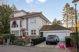 Deze modernistische villa naar ontwerp van architect H. Van Damme is gelegen in de Torentjeslaan te Wemmel, in de gegeerde en rustige wijk Park, met het Marktplein, winkels en openbaar vervoer in de nabije omgeving. De woning dateert van 1937, is solide en gezond, werd steeds zeer goed onderhouden, maar dient vandaag grondig opgefrist te worden. Ze biedt een mooie opportuniteit voor wie ruimte en karakter weet te appreciëren. De villa is opgenomen in de vastgestelde inventaris van het onroerend erfgoed omwille van haar architecturale waarde. Dat betekent dat renovaties mogelijk zijn, maar dat er bij bepaalde werken een vergunning en erfgoedadvies nodig is, vooral om het karakter van de woning te bewaren.”<br />Het gelijkvloers omvat een bureel/eetplaats, een vestiaire met toilet, een lichtrijke living met een prachtig open zicht op de mooie, zonnig georiënteerde tuin, en een aparte, ingerichte keuken. Op de tussenverdieping bevinden zich een bijkomend bureel en een slaapkamer met douchekamer, ideaal als gastenverblijf. De bovenste verdieping beschikt over een nachthal en vier slaapkamers, waarvan één met aansluitende badkamer. <br />De woning is uitgerust met airconditioning in de living en de master bedroom, verwarming op gas en dubbele beglazing. Daarnaast beschikt het eigendom over een afzonderlijke dubbele garage. In de kelderverdieping bevinden zich bovendien een diepe garage, een technisch lokaal en een kelderruimte.