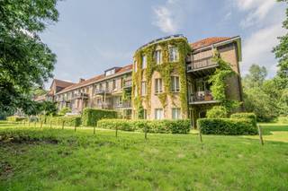 Op zoek naar een karaktervol erfgoedappartement te koop in Halle, vlak bij Brussel? Dit ruime gelijkvloerse appartement van ca. 111 m² beschikt over een inkomhal, een ruime living, een afzonderlijke keuken, een badkamer, een wasplaats, een grote slaapkamer en een kleinere kamer die geschikt is als tweede slaapkamer, bureau, dressing of hobbyruimte.
Het appartement heeft het exclusieve genot van zowel het terras als de aansluitende tuin, die nog moet worden omheind. Zo combineert u het comfort van een appartement met een private buitenruimte in een uitzonderlijk groene omgeving.
De eigendom maakt deel uit van het voormalige sanatorium van Henry Lacoste uit 1927, gelegen op een beschermd privédomein van ongeveer 7 hectare. Via de Ring en het station van Buizingen bereikt u Brussel in ongeveer 15 à 20 minuten.
Voor het gebouw wordt een professioneel renovatieplan uitgewerkt met het oog op een gefaseerde totaalrenovatie, met respect voor het historische en architecturale karakter.
Het appartement wordt aangeboden met een vanafprijs. Een ondergrondse garagebox kan afzonderlijk worden aangekocht vanaf € 25.000.