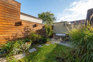 <h1><span> </span></h1><p><span>Een verrassend lichte woning met een warme uitstraling, een prachtige leefkeuken, drie slaapkamers én een gezellige tuin? Die vind je hier, in een aangename, residentiële buurt in Deurne-Zuid. Met z’n mooie mix van hout, staal en betonlook, slimme opbergruimtes en een fijne verbinding met de tuin heeft deze instapklare woning van ca. 121 m² heel wat troeven in huis!</span></p><p><span> </span></p><h3><span>Koken, tafelen en relaxen in het licht</span></h3><p><span>Je komt binnen via de inkomhal, waar je handig je jassen en schoenen kwijt kunt. Van hieruit stap je meteen de grote open keuken binnen, die met z’n warme houten kastenwand en stoere inox afwerking een echte eyecatcher is. Het grote kookeiland met chromen werkblad, geïntegreerde spoelbak en gezellige zitplek nodigt uit om samen te aperitieven terwijl er gekookt wordt. Je hebt hier een vijfpits gasvuur, dampkap, oven, ingebouwde vaatwasser en vooral héél veel kastruimte. Een grote ramenpartij zorgt voor natuurlijk licht en verluchting.</span></p><p><span>Aansluitend kom je in de gezellige leefruimte, waar de donkere vloer mooi contrasteert met de lichte muren en warme houten accenten. Er is volop plaats voor een grote eettafel en een comfortabele zithoek. De zwarte industriële schuifdeuren met glas geven het geheel extra karakter en schermen de trap, de gang, het gastentoilet met handenwasser en een handige berging stijlvol af.</span></p><p><span>Achteraan trekt de grote lichtkoepel extra daglicht naar binnen, terwijl het kamerbrede schuifraam de tuin helemaal bij de leefruimte betrekt. Zodra het zonnetje schijnt, zet je de deur open en loopt binnen moeiteloos over in buiten. In de groene tuin geniet je van een stukje gazon, siergrassen, planten en een gezellig terras waar je heerlijk kunt tafelen. </span></p><p><span> </span></p><h3><span>Warme parketvloeren en een badkamer met alles erop en eraan</span></h3><p><span>Via de houten trap met sfeervolle ingebouwde verlichting ga je naar de eerste verdieping. Op de overloop ligt een mooie parketvloer en vind je een hele reeks ingemaakte kasten. Ideaal om kleding, beddengoed en allerlei spullen netjes uit het zicht op te bergen.</span></p><p><span>De ruime slaapkamer van ca. 13 m² heeft dezelfde warme parketvloer, een groot raam en een strak, verticaal verwarmingselement. Een fijne plek om helemaal tot rust te komen.</span></p><p><span>De badkamer is een echte wellnessplek, met een moderne grijze tegelvloer, een ruime inloopdouche in betonlook met regendouche én een ligbad. Het brede badkamermeubel heeft twee witte opzetlavabo’s, ingebouwd kraanwerk en heel wat opbergruimte. De grote spiegel met houten omlijsting zorgt voor een warm accent. Je hebt hier ook een hangtoilet, een zwarte industriële radiator met handdoekdrager en twee ramen voor natuurlijk licht en verluchting.</span></p><p><span> </span></p><h3><span>Twee gezellige kamers onder het dak</span></h3><p><span>Via de stoere zwarte stalen trap met houten treden bereik je de tweede verdieping. Hier vind je nog twee gezellige slaapkamers, allebei met een parketlaminaatvloer en een groot Veluxraam dat voor veel daglicht zorgt. De schuine dakvlakken geven de kamers extra charme en dankzij de ingemaakte kasten onder het dak gaat er geen plaats verloren. Perfect als kinderkamers, logeerkamer of thuisbureau. Ook op de overloop vind je nog extra kastruimte.</span></p><p><span> </span></p><p><span>Rustig wonen met alles dichtbij</span></p><p><span>De Waterbaan ligt in een aangename, residentiële buurt in Deurne-Zuid, waar je rustig woont en toch alles binnen handbereik hebt. Voor je dagelijkse boodschappen kun je terecht bij de buurtwinkels en supermarkten in de omgeving van de Herentalsebaan. Ook scholen, andere voorzieningen en de herkenbare Sint-Rochuskerk liggen vlakbij.</span></p><p><span>De tramhalte Deurne Waterbaan bevindt zich op wandelafstand, net als verschillende bushaltes. Zo verplaats je je vlot richting het centrum van Antwerpen en de omliggende wijken. Een fijne locatie dus voor wie graag rustig woont, maar de stad niet wil missen!</span></p><p><span> </span></p><p><span> </span></p>